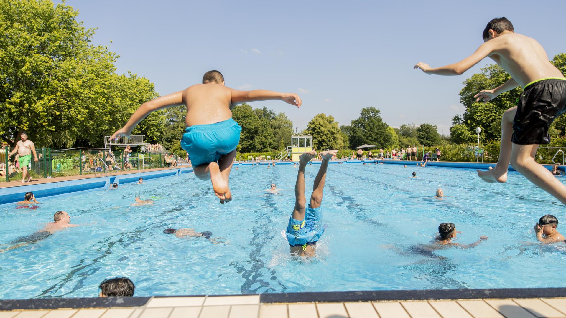 Jungs springen in das Badebecken. 