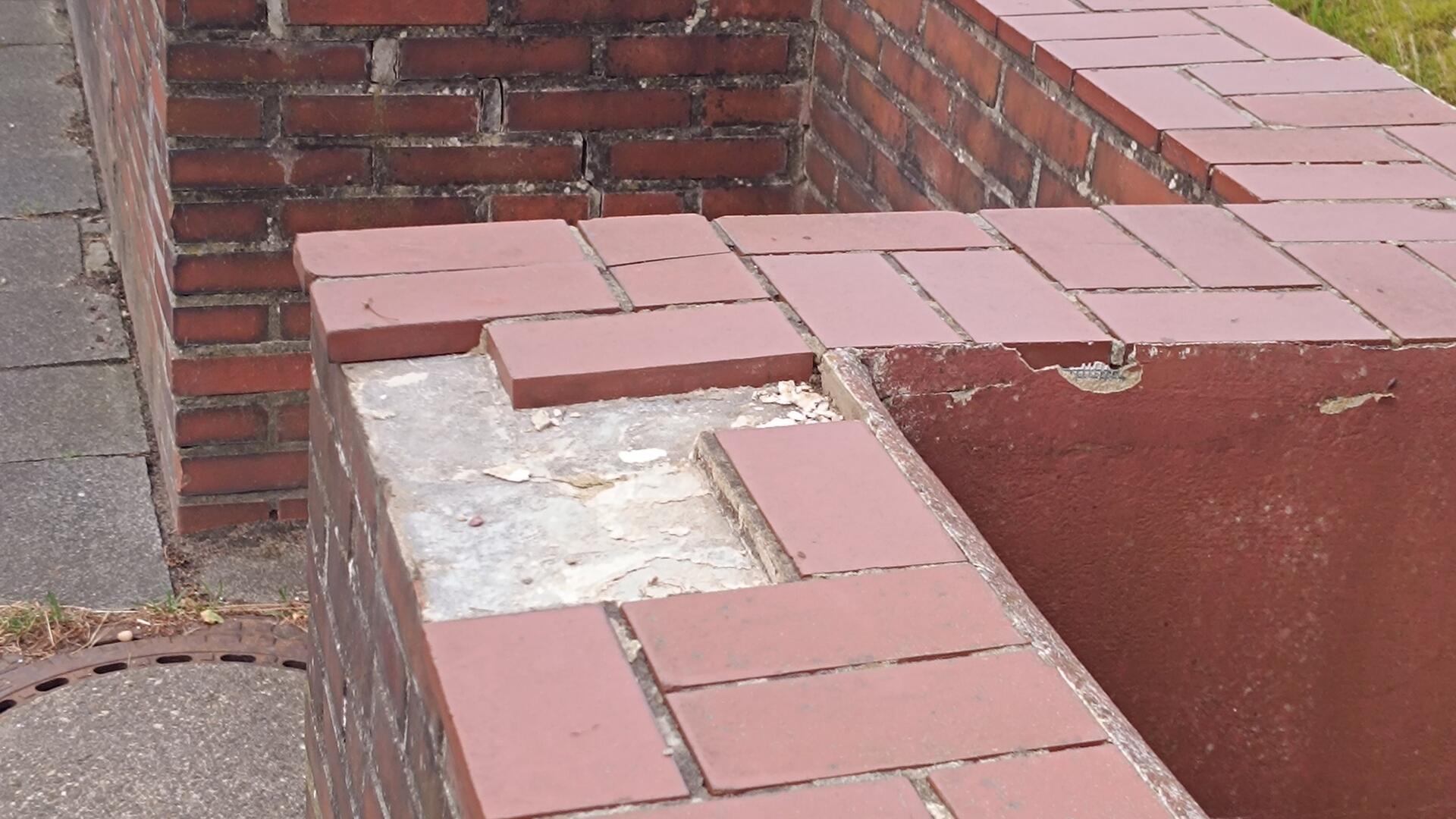 Eine Friedhofsmauer. An einigen Stellen fehlen Steine. 