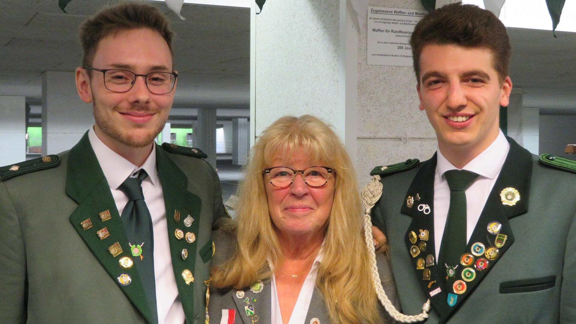 Zwei Männer und eine Frau stehen nebeneinander und gucken in die Kamera.