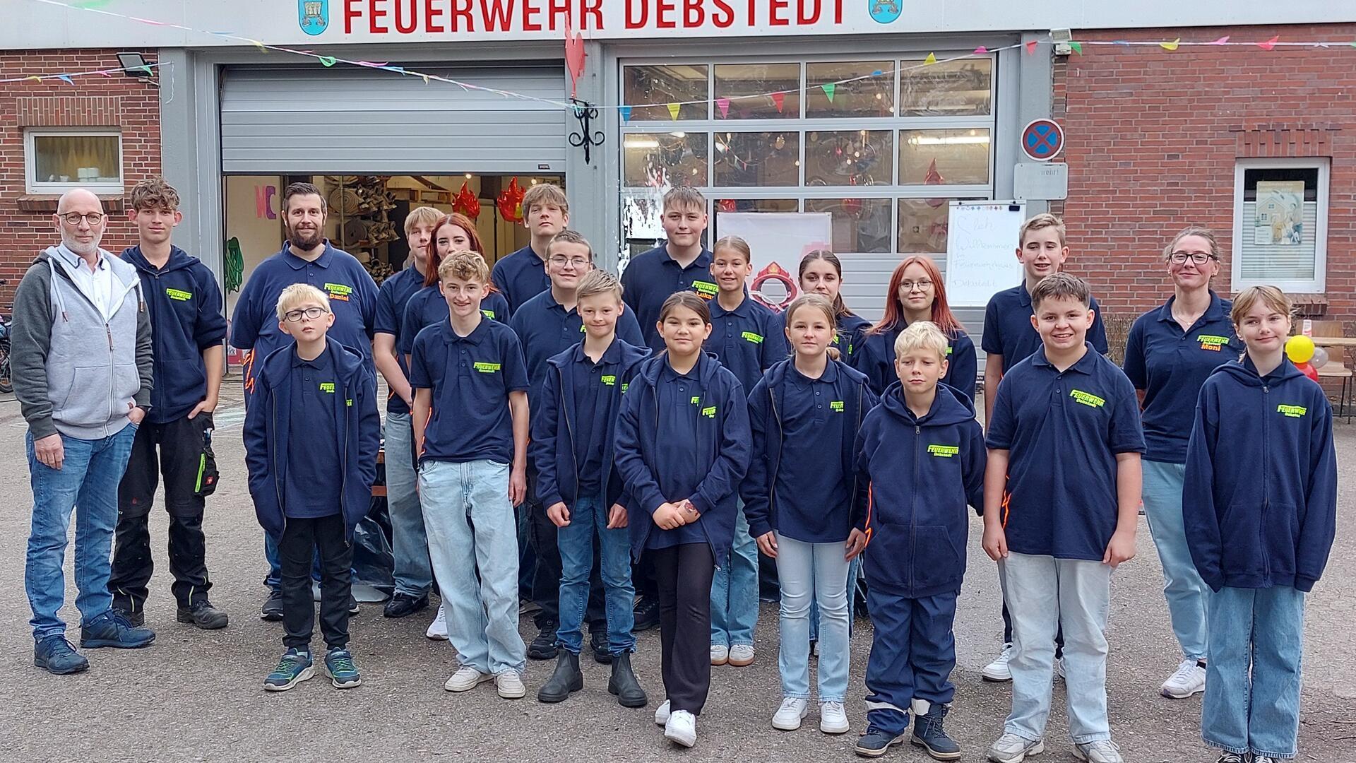 Eine Gruppe junger Menschen steht vor einem Feuerwehrgebäude 