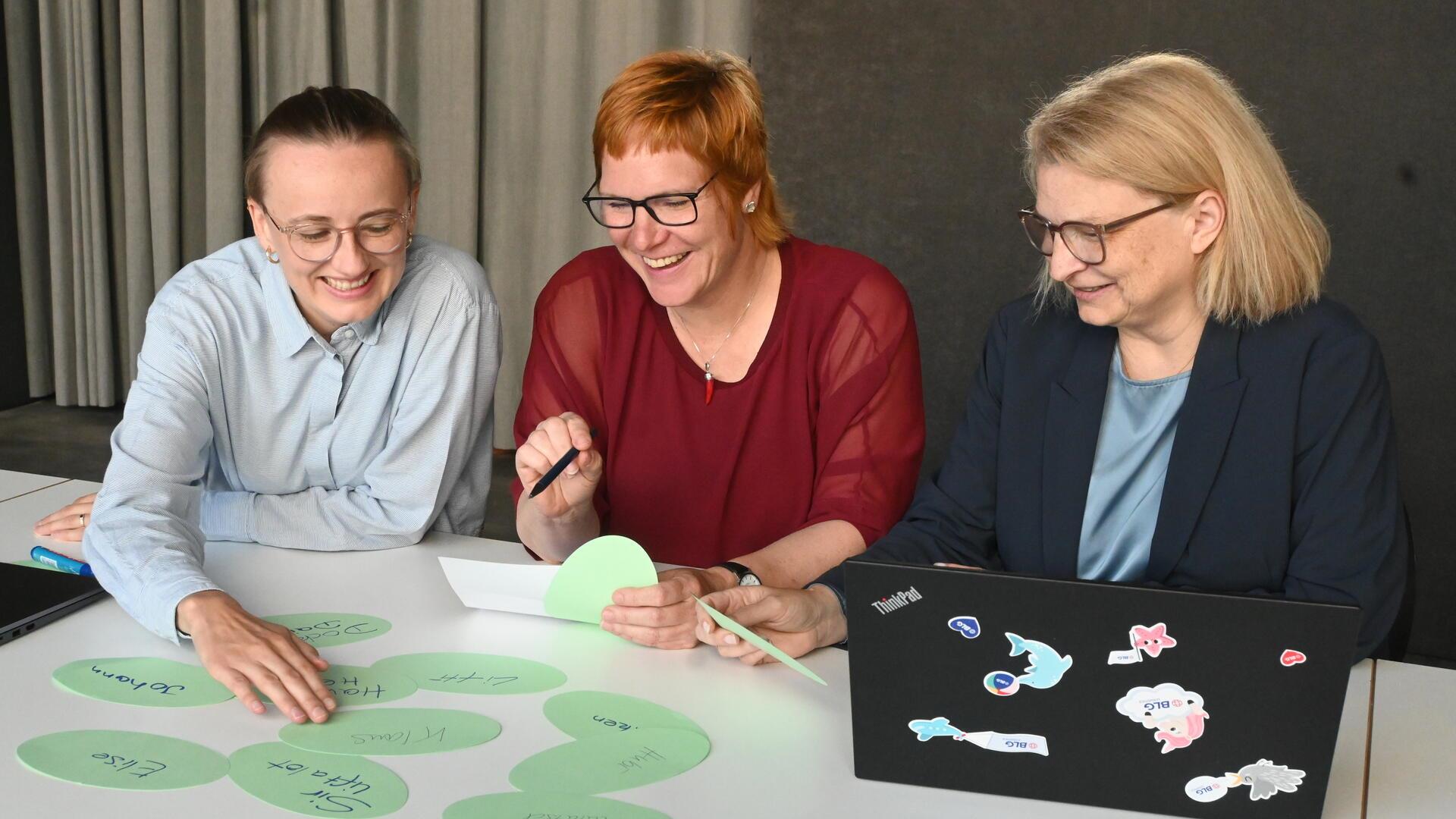 Drei Frauen schauen auf eine Auswahl.