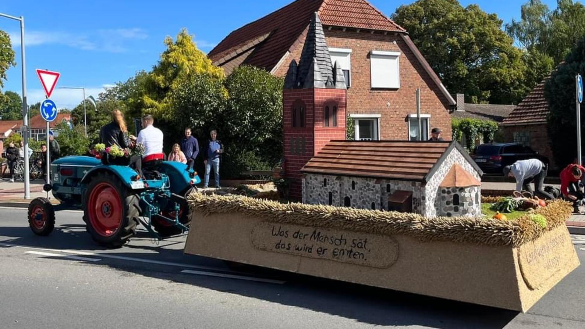 Ein Anhänger mit dem Modell einer Kirche, der von einem Trecker gezogen wird.