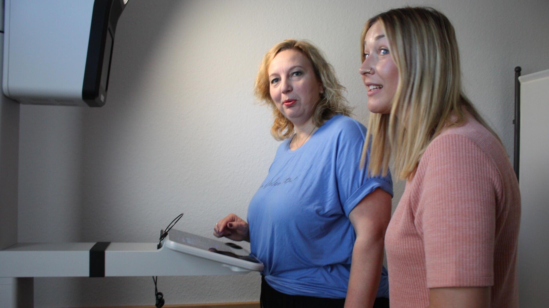 Zwei Frauen stehen im Bürgeramt am PointID-Gerät. Eine von ihnen bedient das Display, die andere steht beratend daneben.