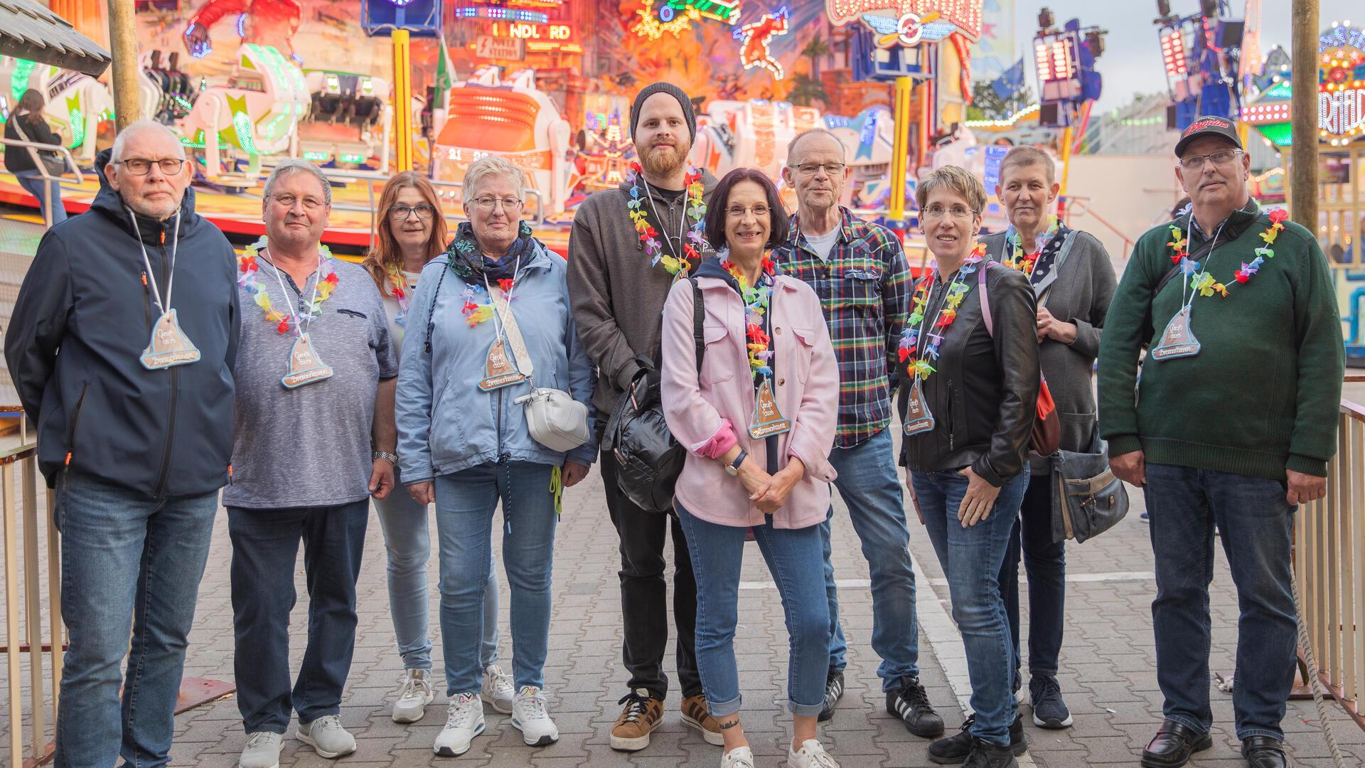 Eine Gruppe Menschen steht vor einem Fahrgeschäft auf dem Jahrmarkt