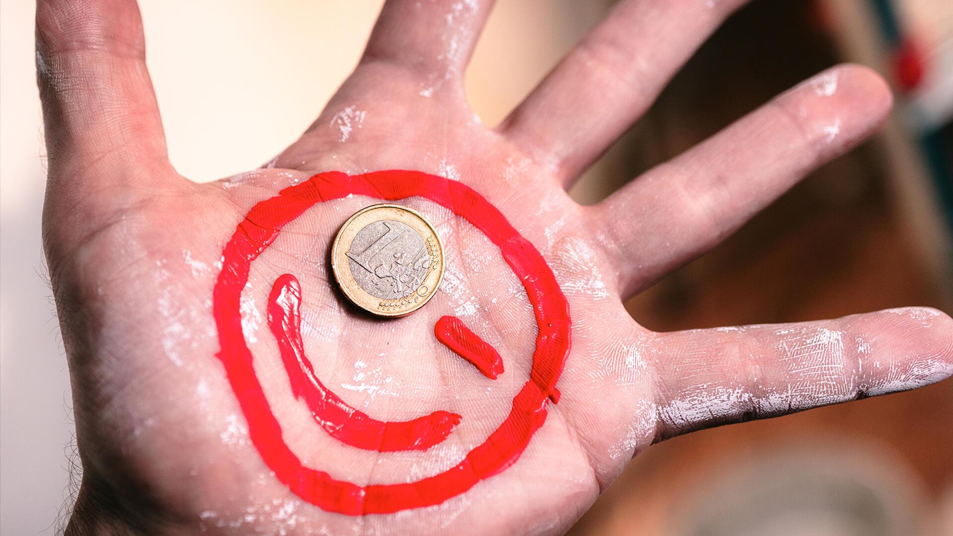 Ein Maler-Euro-Smiley auf eine Hand gemalt.