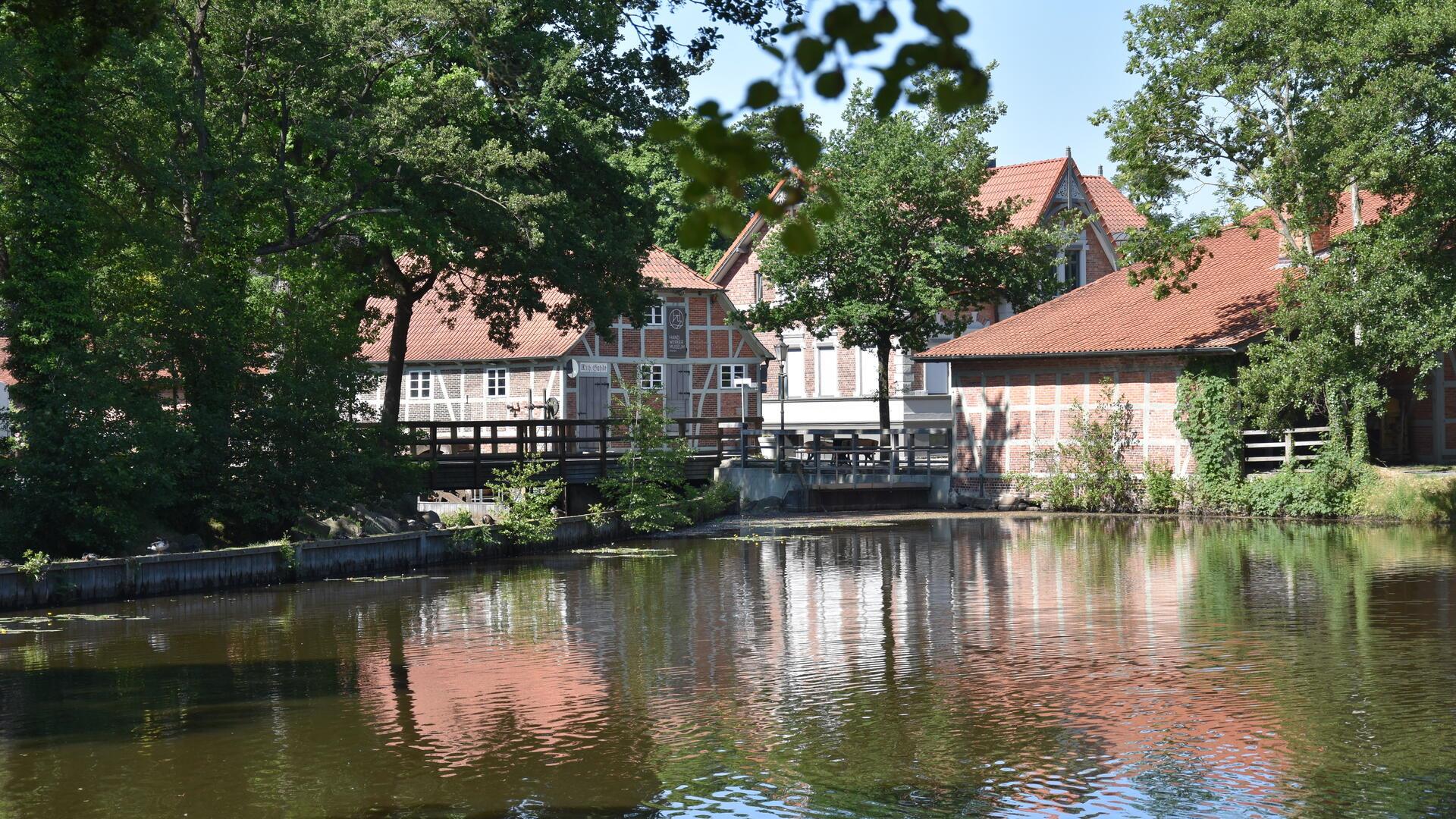 Ein Ensemble historischer Gebäude am Ufer eines Mühlenteiches.
