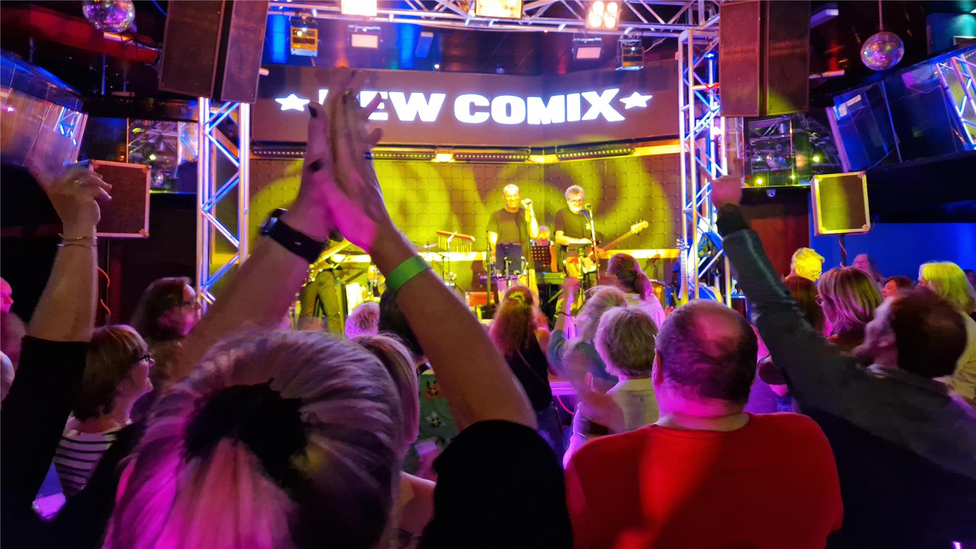 Eine Bühne mit einer Band, davor tanzende und klatschende Fans.