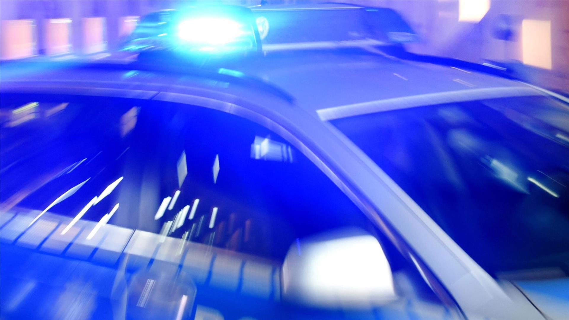 Ein Streifenwagen der Polizei steht mit eingeschaltetem Blaulicht auf der Straße.