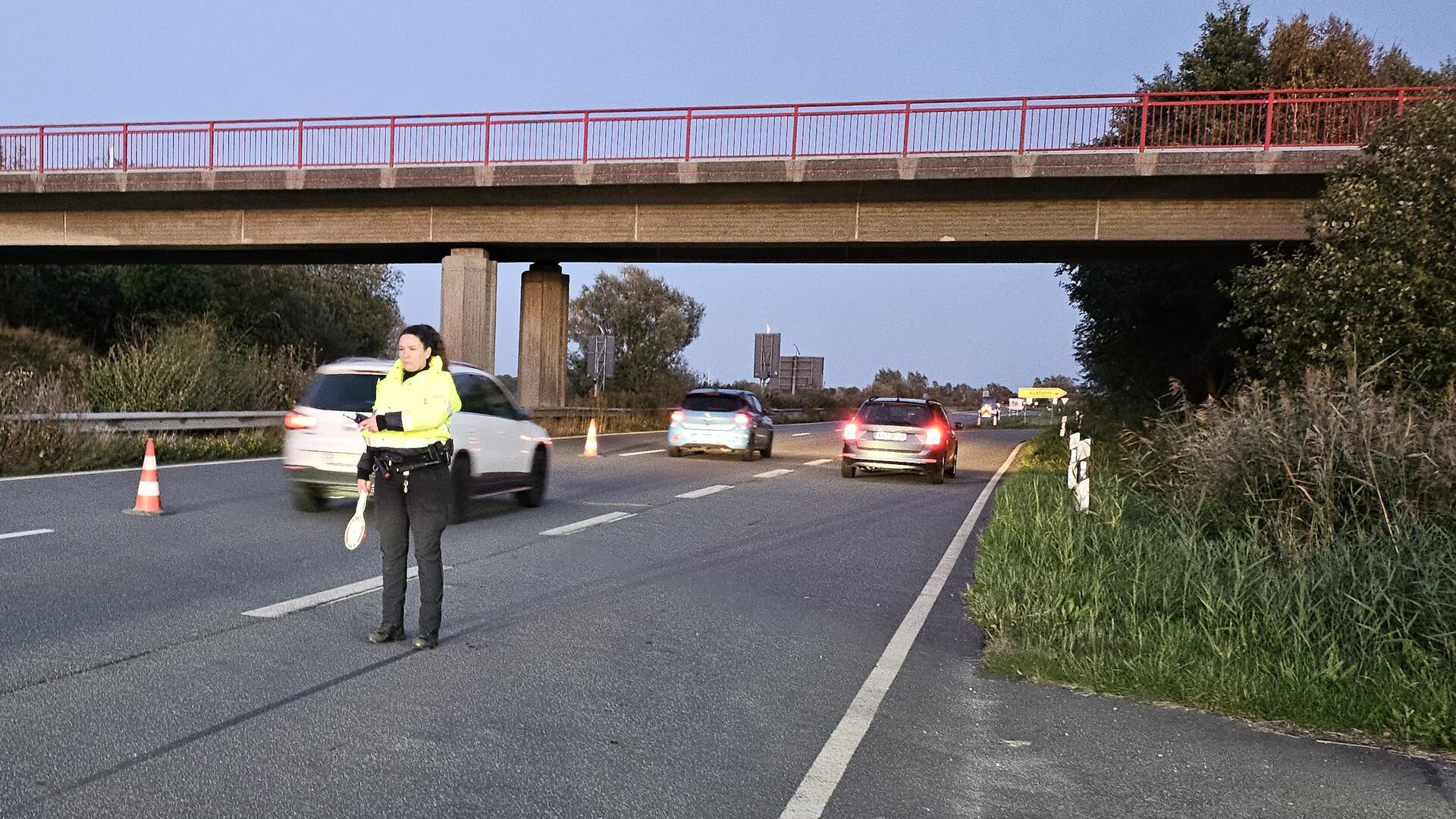 Eine Polizistin steht auf einer Autobahn und regelt den Verkehr.