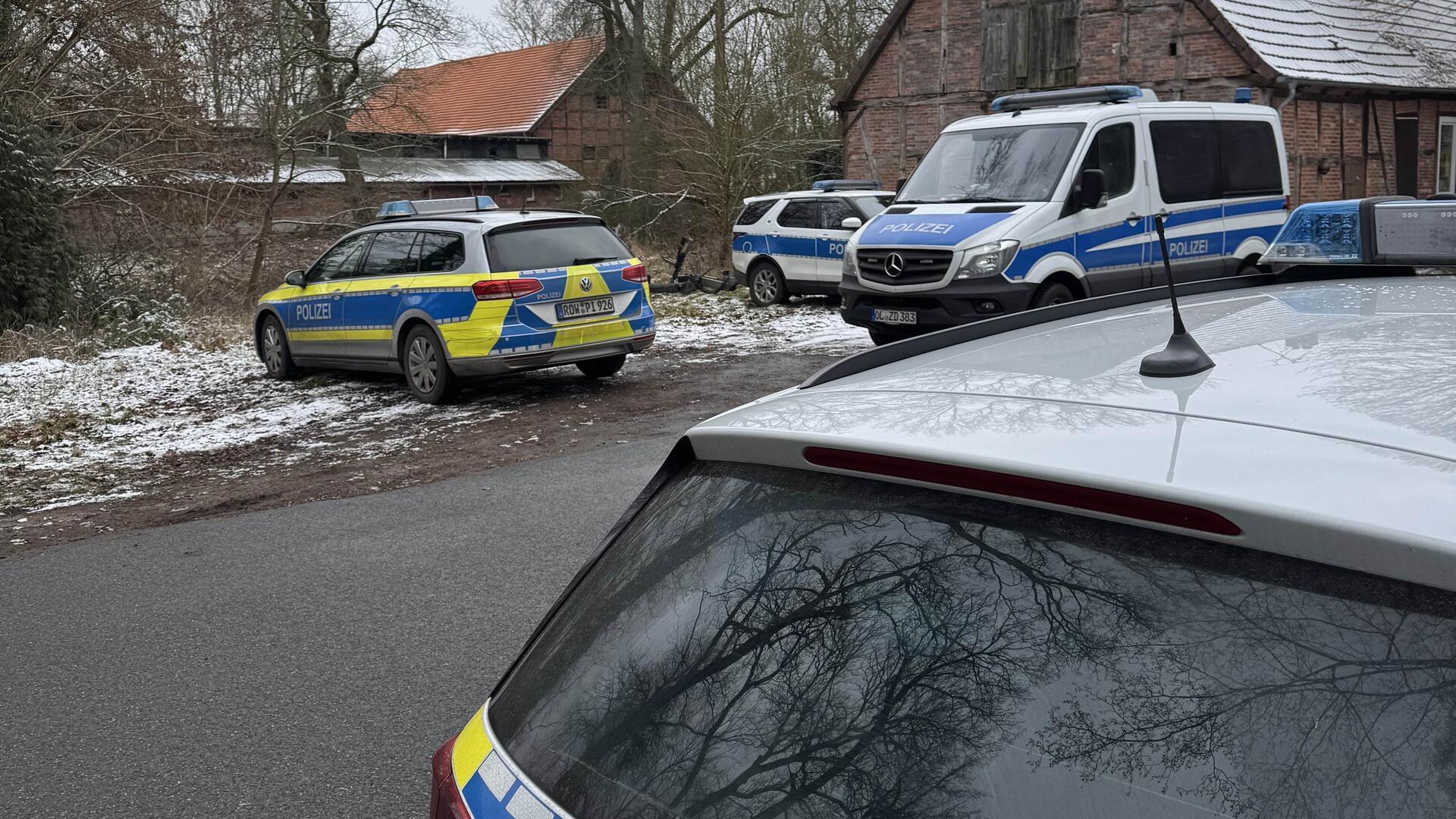 Mehrere Polizeifahrzeuge stehen an einer Straße.