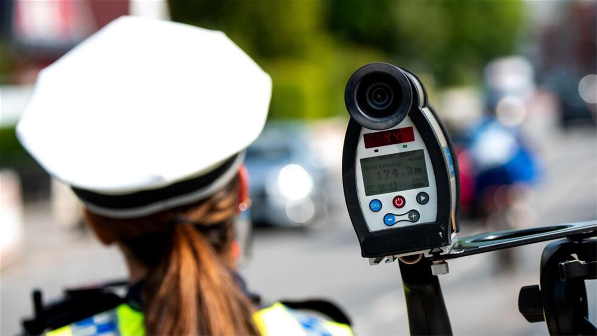 Eine Polizistin misst mit einem Laser die Geschwindigkeit eines Autos