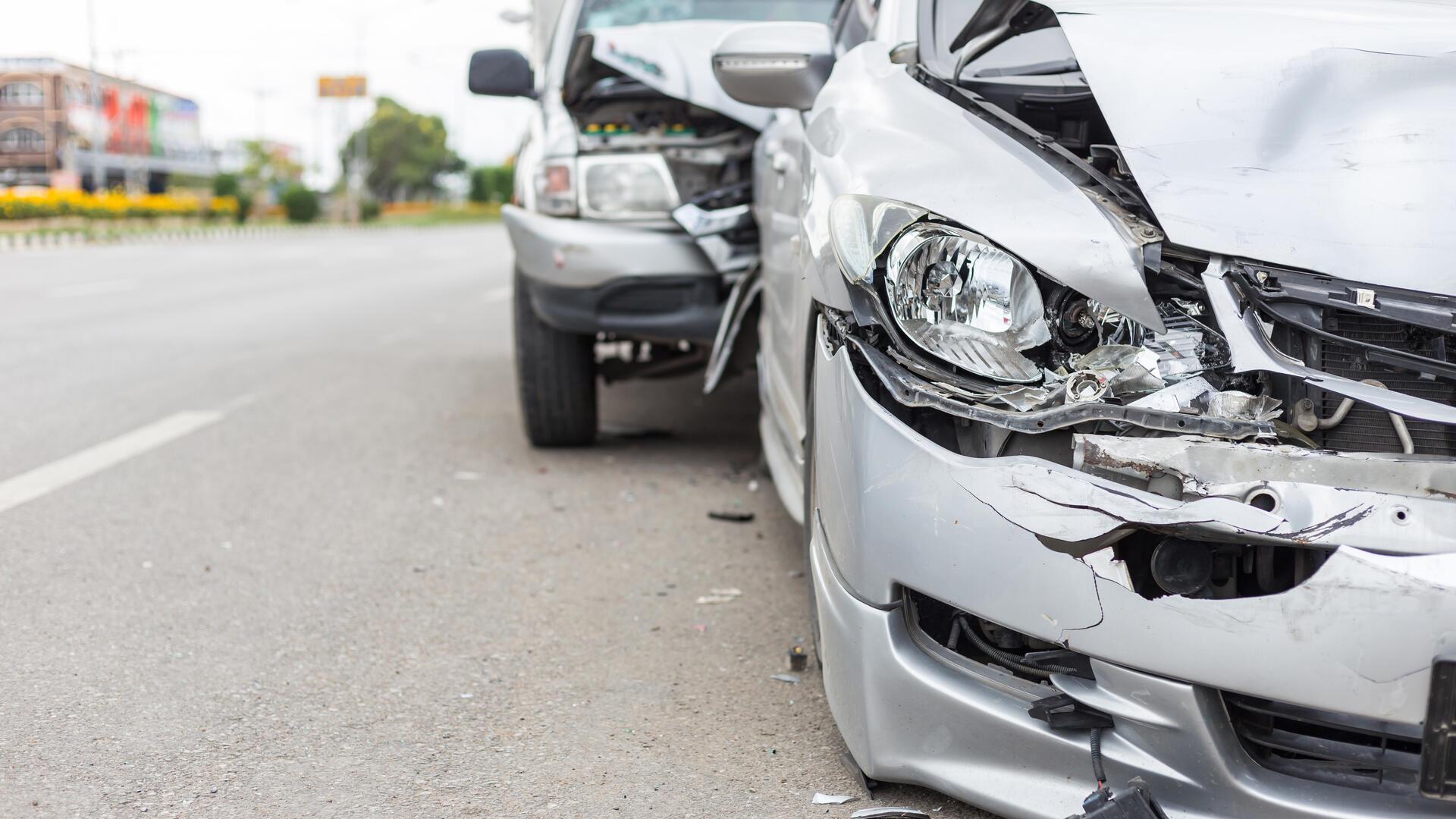 Blaues Balkendiagramm mit verunfalltem, silbernen Auto im Hintergrund