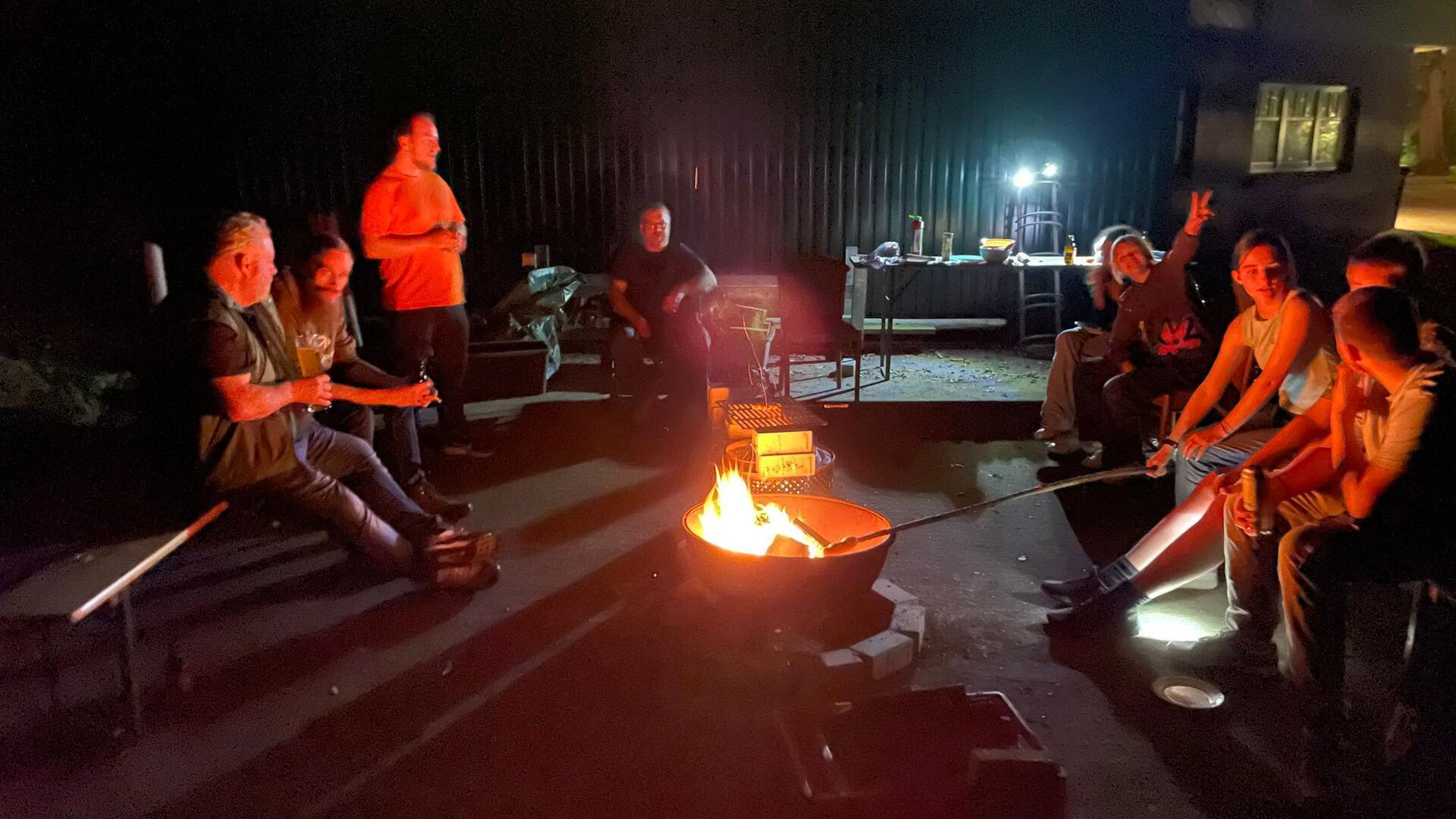 Jugendliche und Betreuer sitzen um eine Feuerschale herum