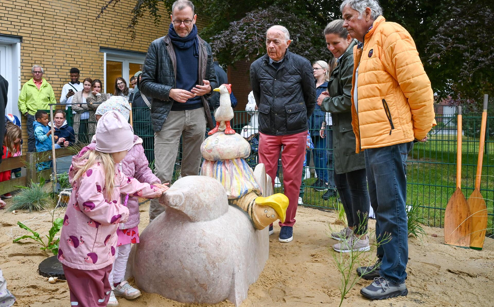 Kinder und Erwachsene stehen rund um eine Skulptur aus Ton, die Robbe, Wattwurm, Qualle und Möwe zeigt.