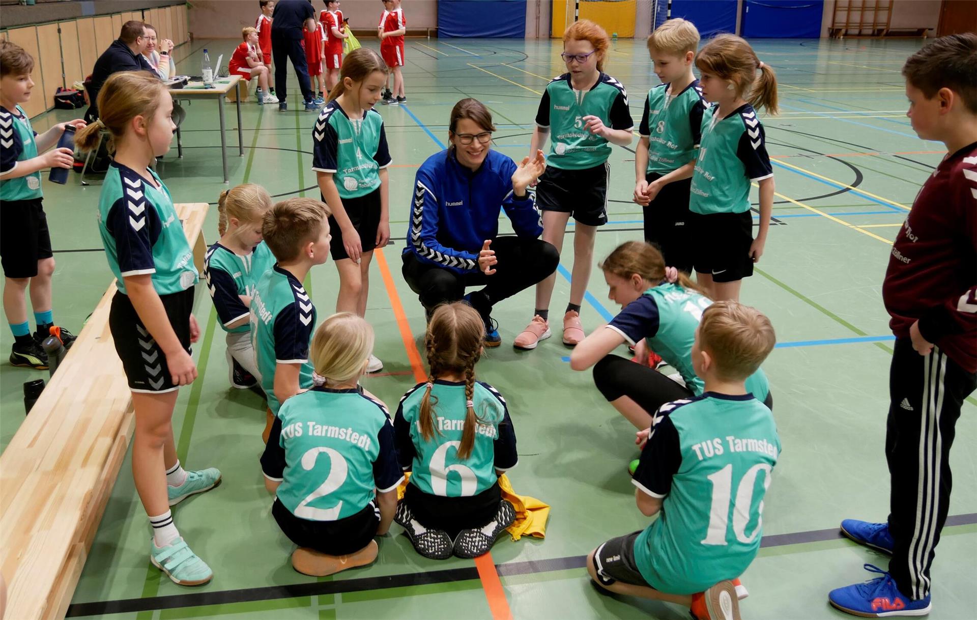 Die Spieler und Spielerinnen hören Trainerin Vilja Bartschies in der Auszeit aufmerksam zu.