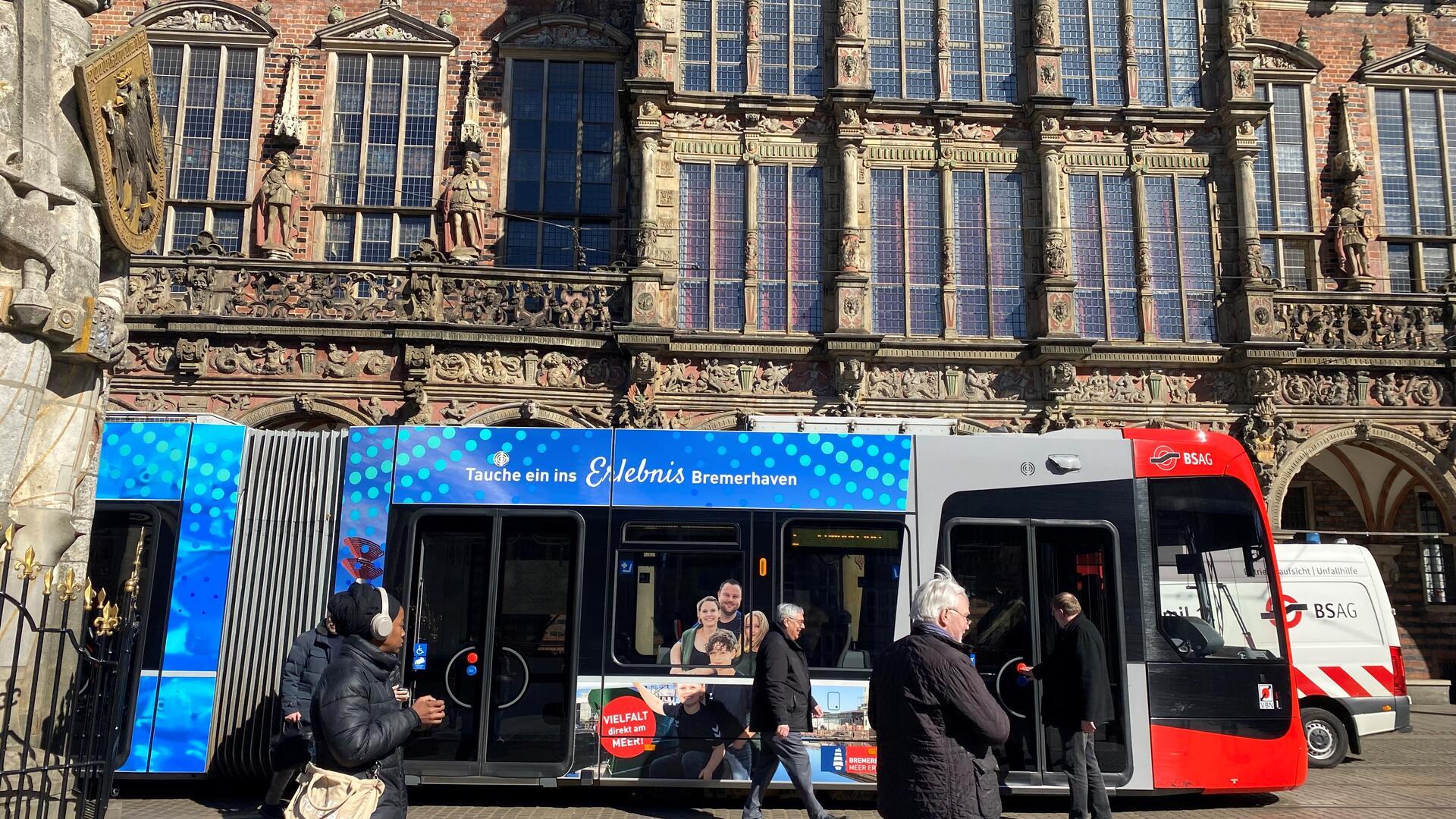 Die Straßenbahn namens „Nordlicht“ fährt mit Bremerhaven-Motiven zwei Jahre lang durch Bremen. Oberbürgermeister Melf Grantz (Mitte) steigt am Bremer Rathaus zur Probefahrt ein. 