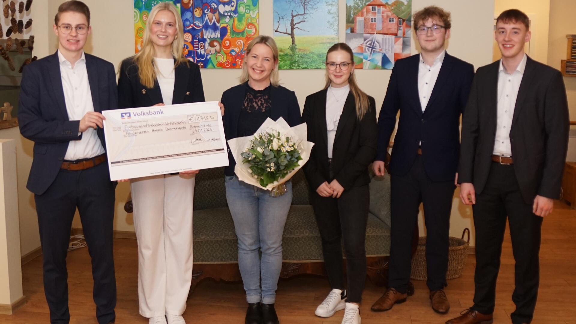 Die Volksbank-Azubis Matthias Wende (von links), Lenja Böschen, Leonie Augustin (Vierte von links), Jonas Kröger und Tristan Baron überreichten vor Kurzem den symbolischen Spendenscheck in Höhe von 1.713 Euro an Sarah Mangels (mit Blumenstrauß), zweite Vorsitzende des Fördervereins Hospiz zwischen Elbe und Weser.