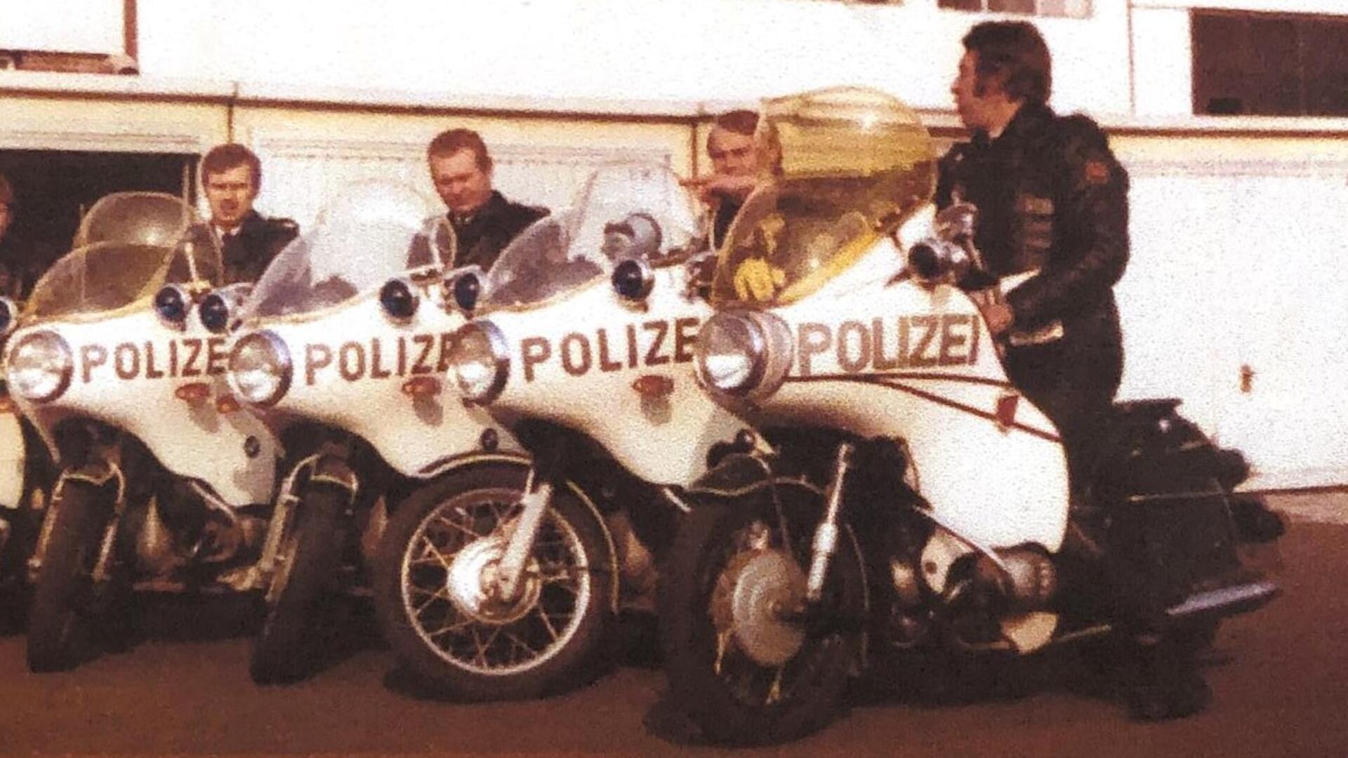 Historisches, leicht verblasstes Foto von vier Polizisten in Lederjacken auf klassischen Polizeimotorrädern. Auf den weißen Maschinen steht deutlich „POLIZEI“.