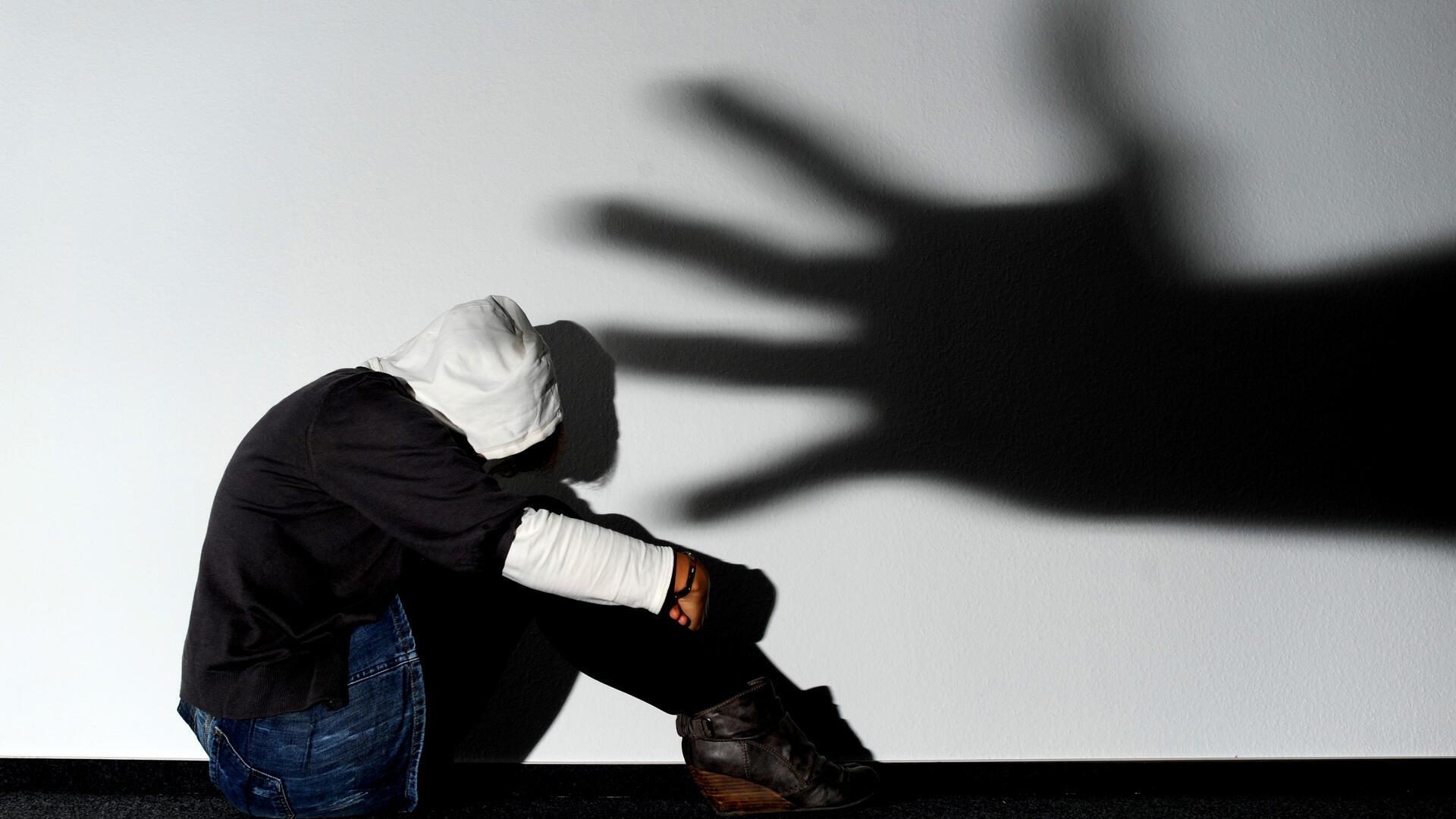 Schatten einer Hand über sitzender Frau. 