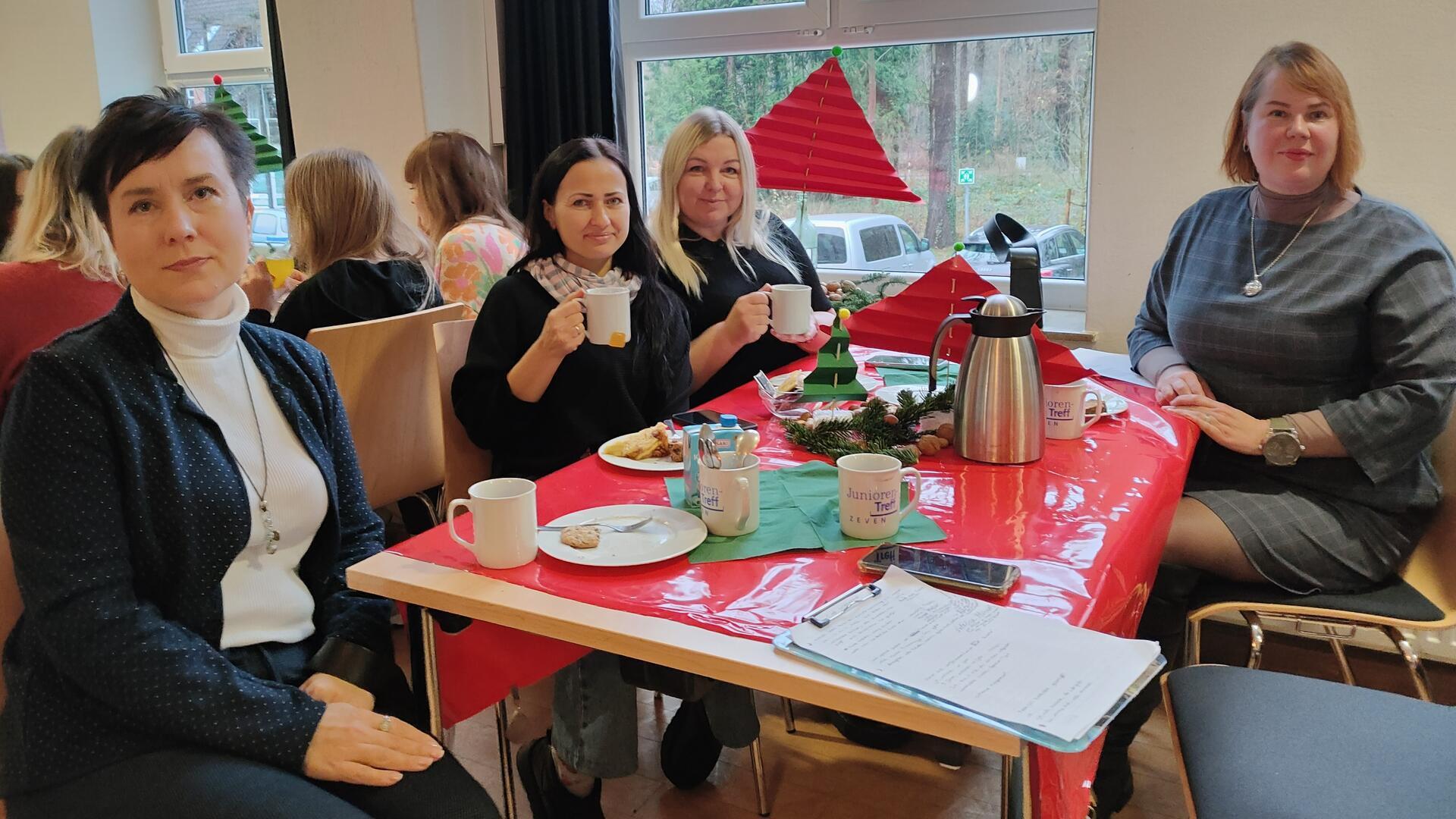 Vier Frauen sitzen um einen Tisch herum und trinken Kaffee.