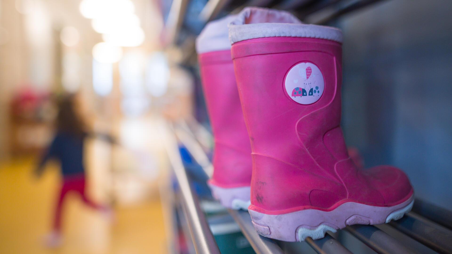 Blick in eine Kita. Lilafarbene Stiefel sind rechts zu sehen, links unscharf ein Kind. Die von der Gewerkschaft Verdi angekündigten Warnstreiks am Freitag könnten zu deutlichen Einschränkungen, besonders in den Kitas in Bremerhaven und dem Cuxland, führen.