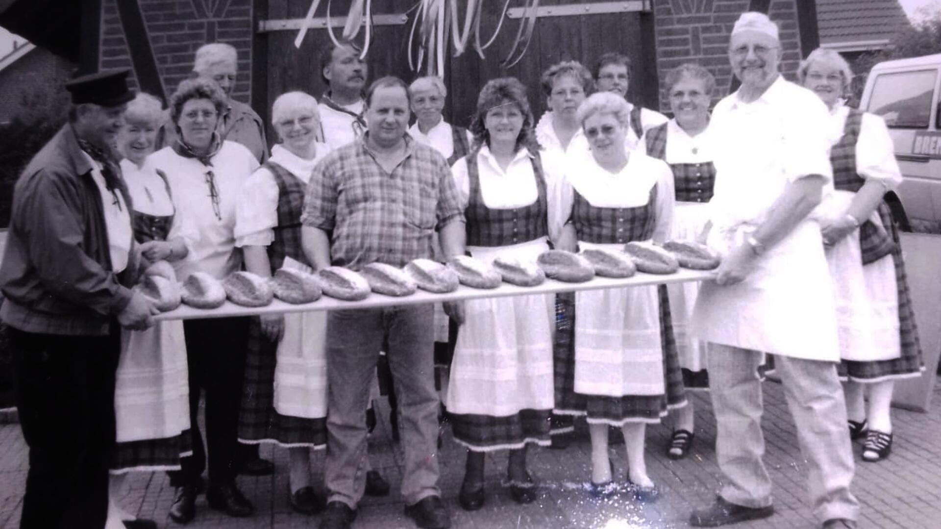 Mehrere Menschen halten ein langes Brett mit frischen Backwaren in die Höhe.