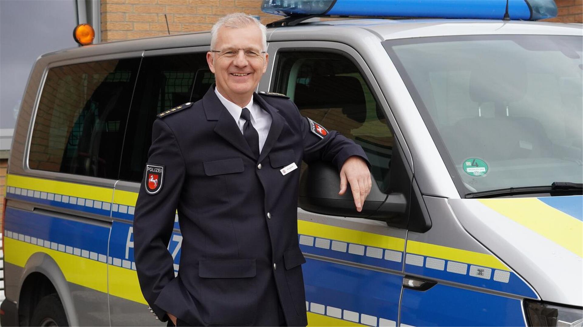 Ein Mann in einer dunklen Uniform steht an einem Fahrzeug mit blauen und gelben Streifen.