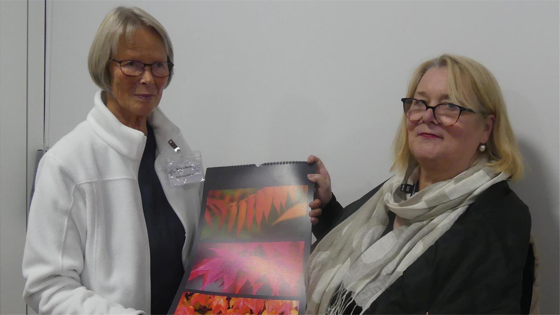 Dorothea Belmer (links) zeigt Kirsten Fischer einen ihrer großformatigen Kalender.