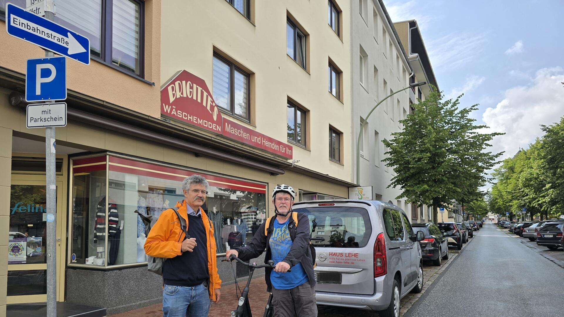 Zwei Männer mit einem Fahrrad an der Einfahrt zu einer Einbahnstraße