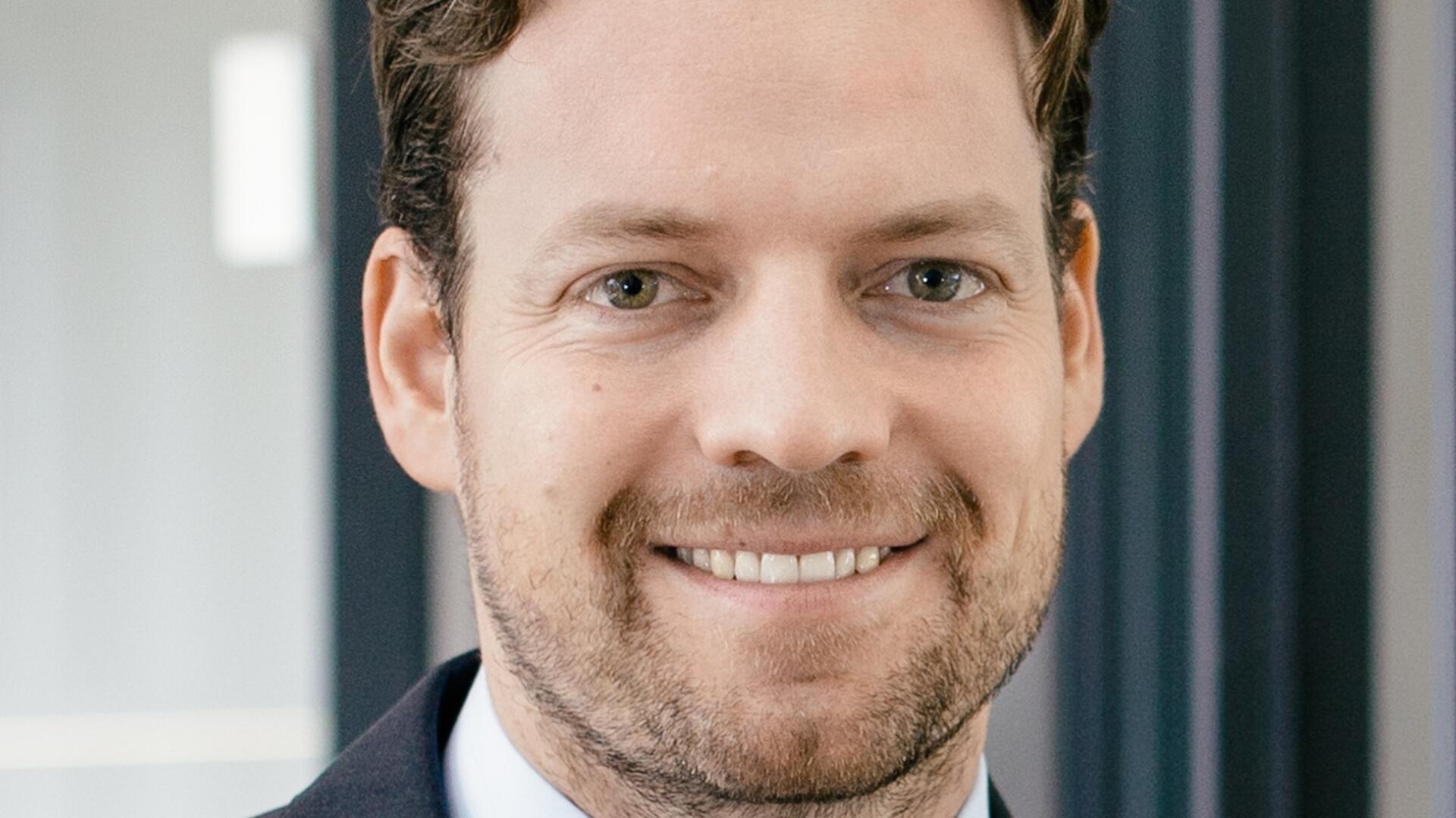 ein Mann mit Bart lächelt in die Kamera