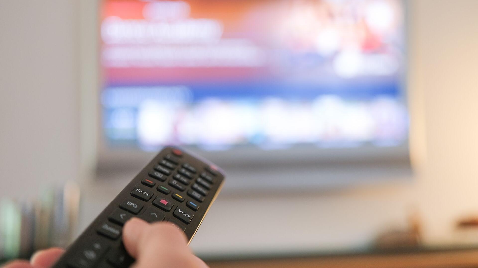 Eine Hand bedient eine Fernbedienung für ein TV-Gerät. (zu dpa: «Vodafone steckt im TV-Geschäft im Abwärtssog»)