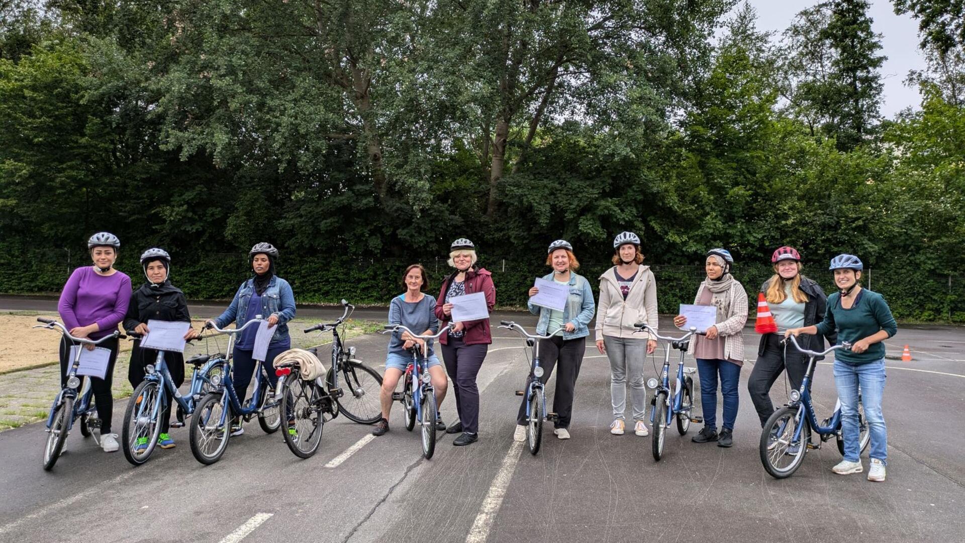 Zehn Frauen mit acht Fahrrädern stehen nebeneinander auf einem Platz für Verkehrstraining