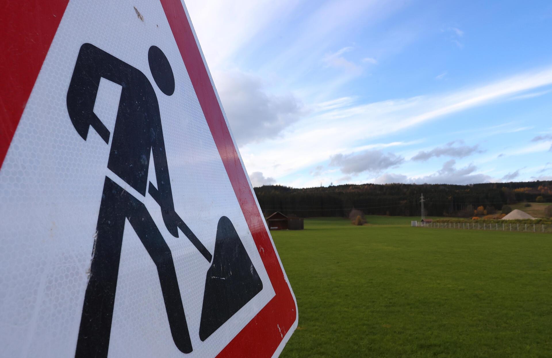 Ein Baustellenschild steht vor einer grünen Wiese: Die Gemeinde Breddorf möchte Bauland anbieten. Doch das Verfahren verzögert sich.