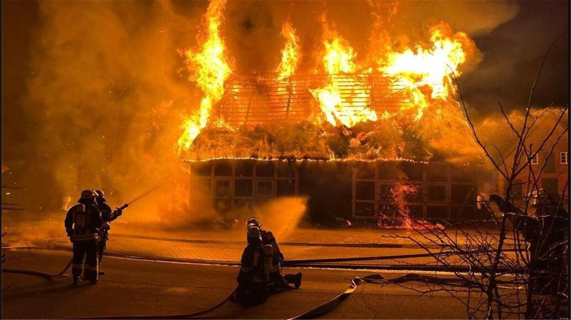 Feuerwehrleute  löschen ein brennendes Reetdachhaus. In Dollern ist es in der Nacht zu Donnerstag zu einem Großbrand gekommen, bei dem mehrere Häuser vernichtet wurden.