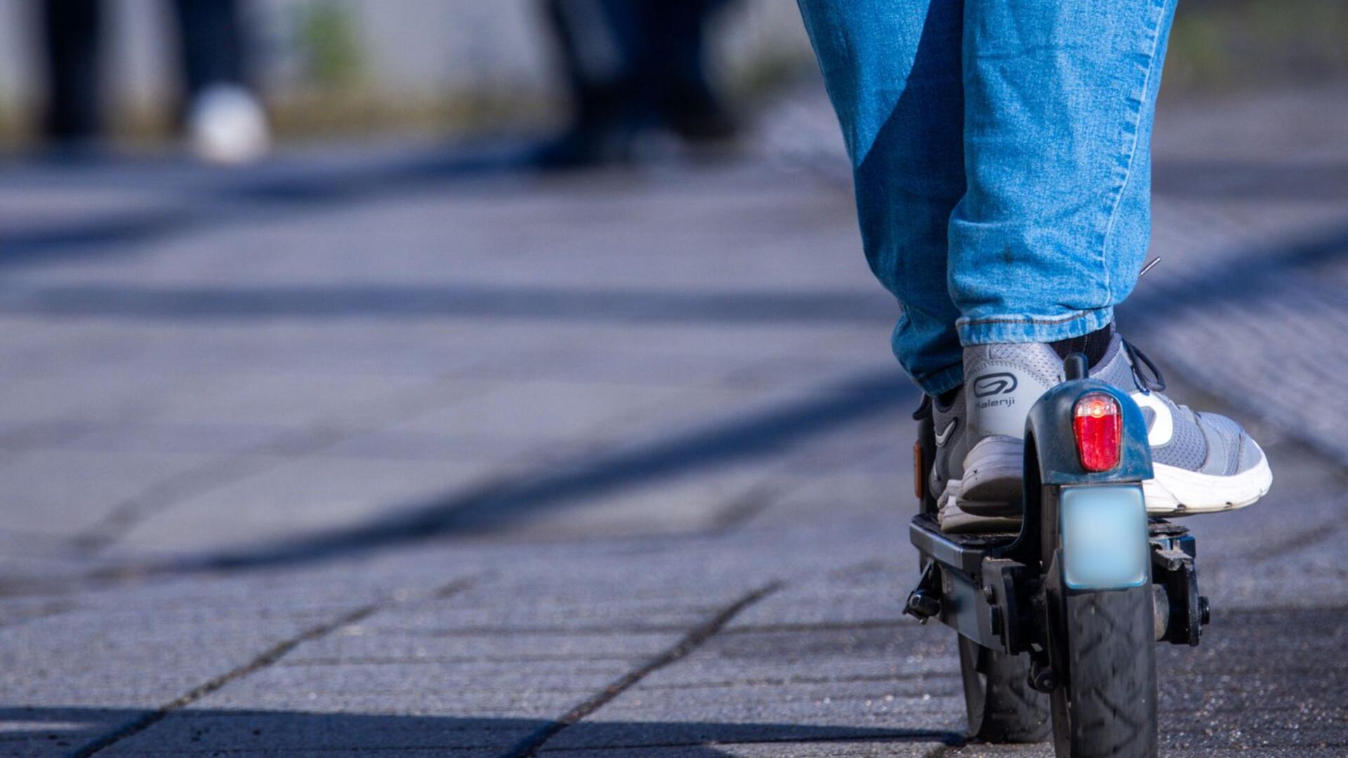 Ein Reisender fährt mit seinem E-Scooter über einen Bahnsteig.
