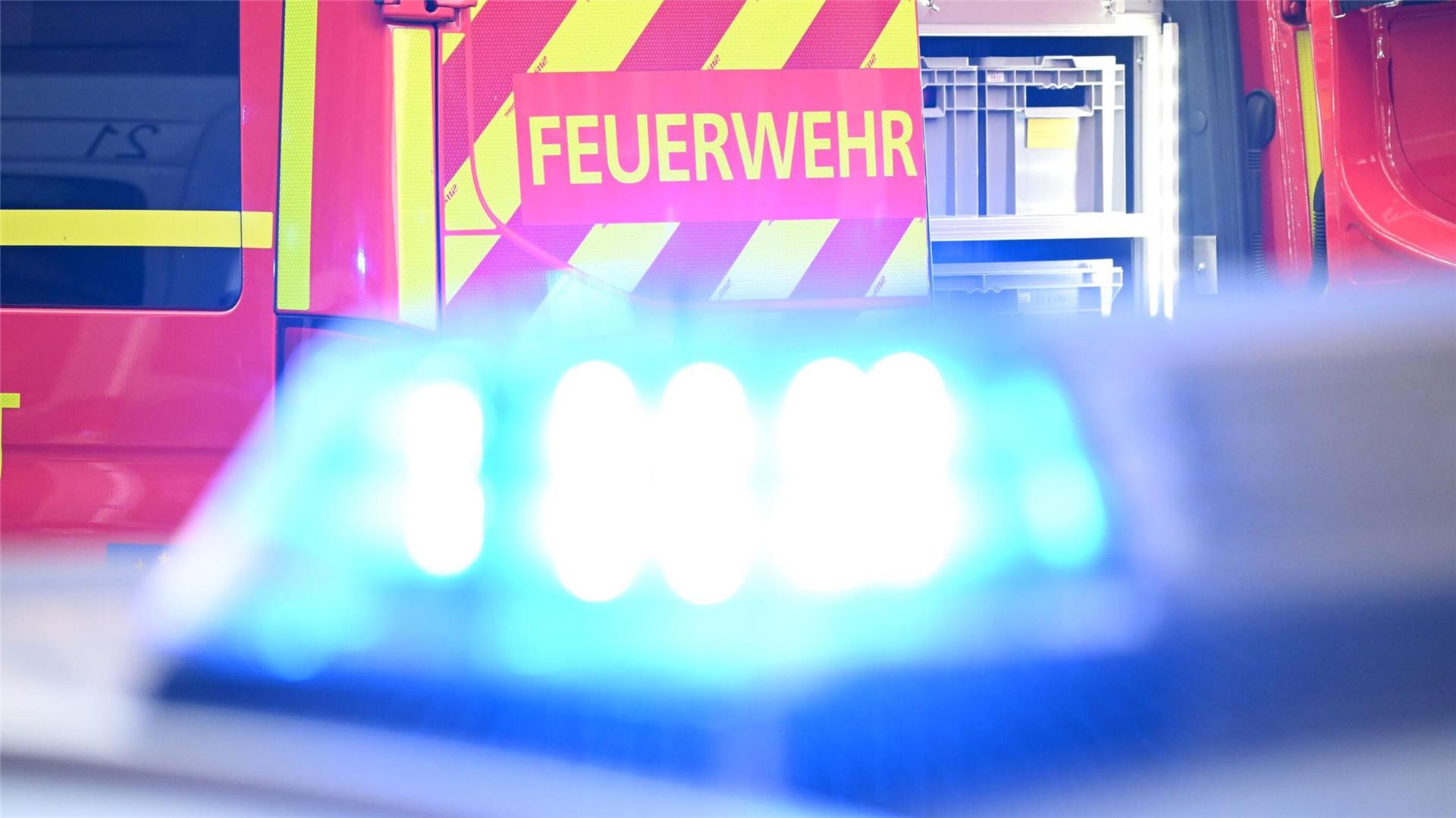 Im Vordergrund Blaulicht und im Hintergrund ein Fahrzeug mit der Aufschrift Feuerwehr.