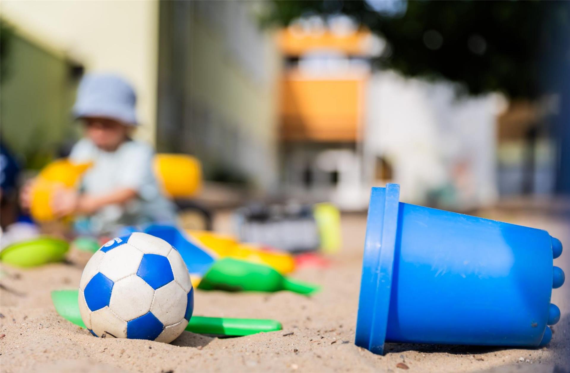 Ein Kind spielt im Sandkasten einer Kita.