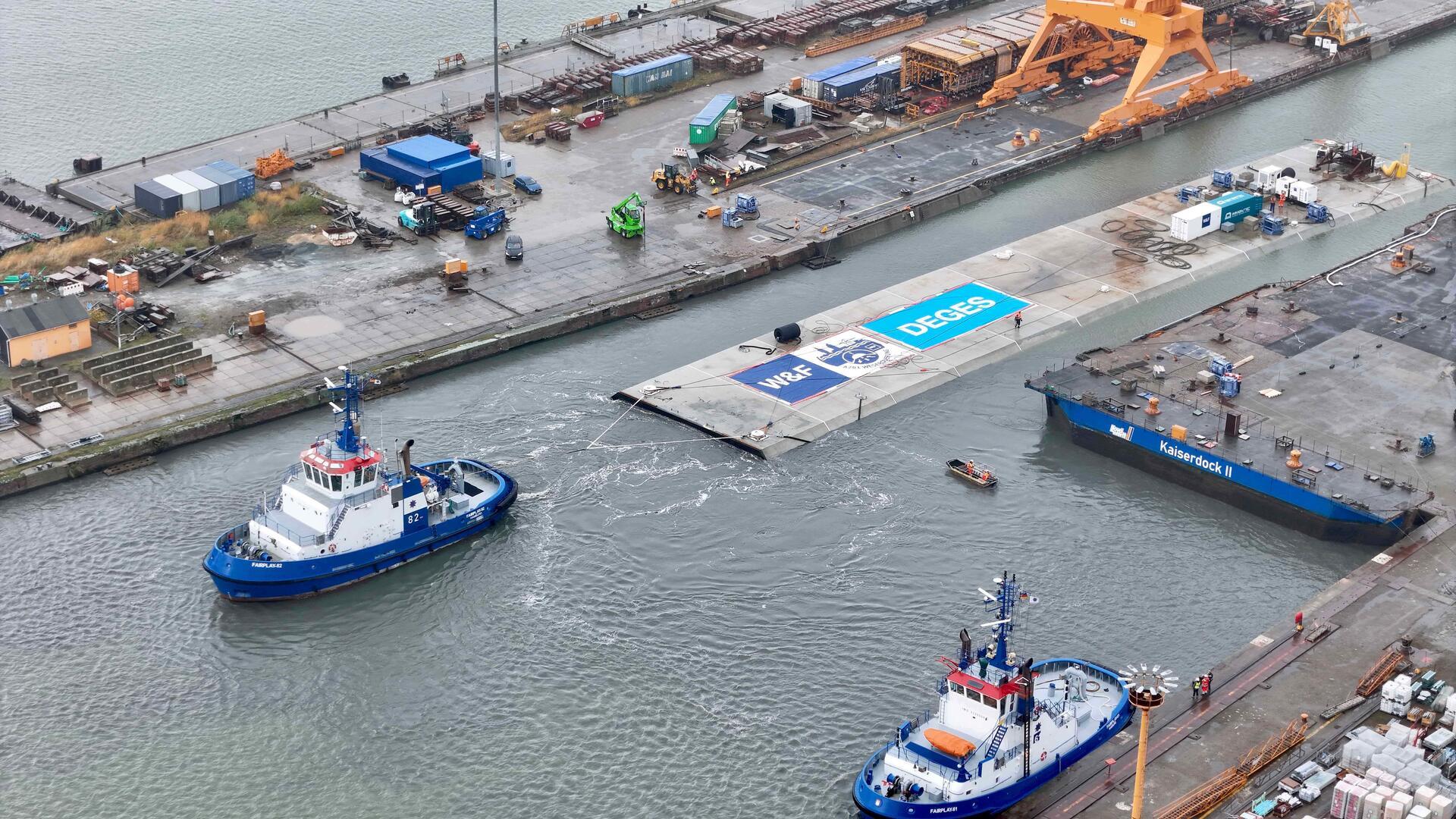 Hier schwimmen 20.000 Tonnen Beton: Elemente für Wesertunnel gehen auf Reise Ein Schlepper zieht das riesige Betonelement aus dem Dock.