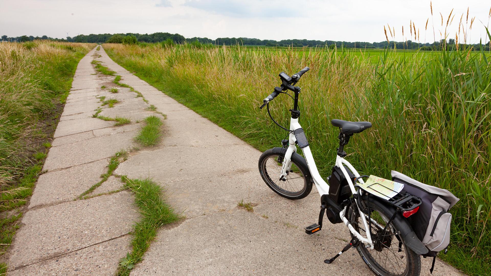 Sanierungsbedürftiger Wirtschaftsweg mit Fahrrad in der Gemeinde Wurster Nordseeküste.