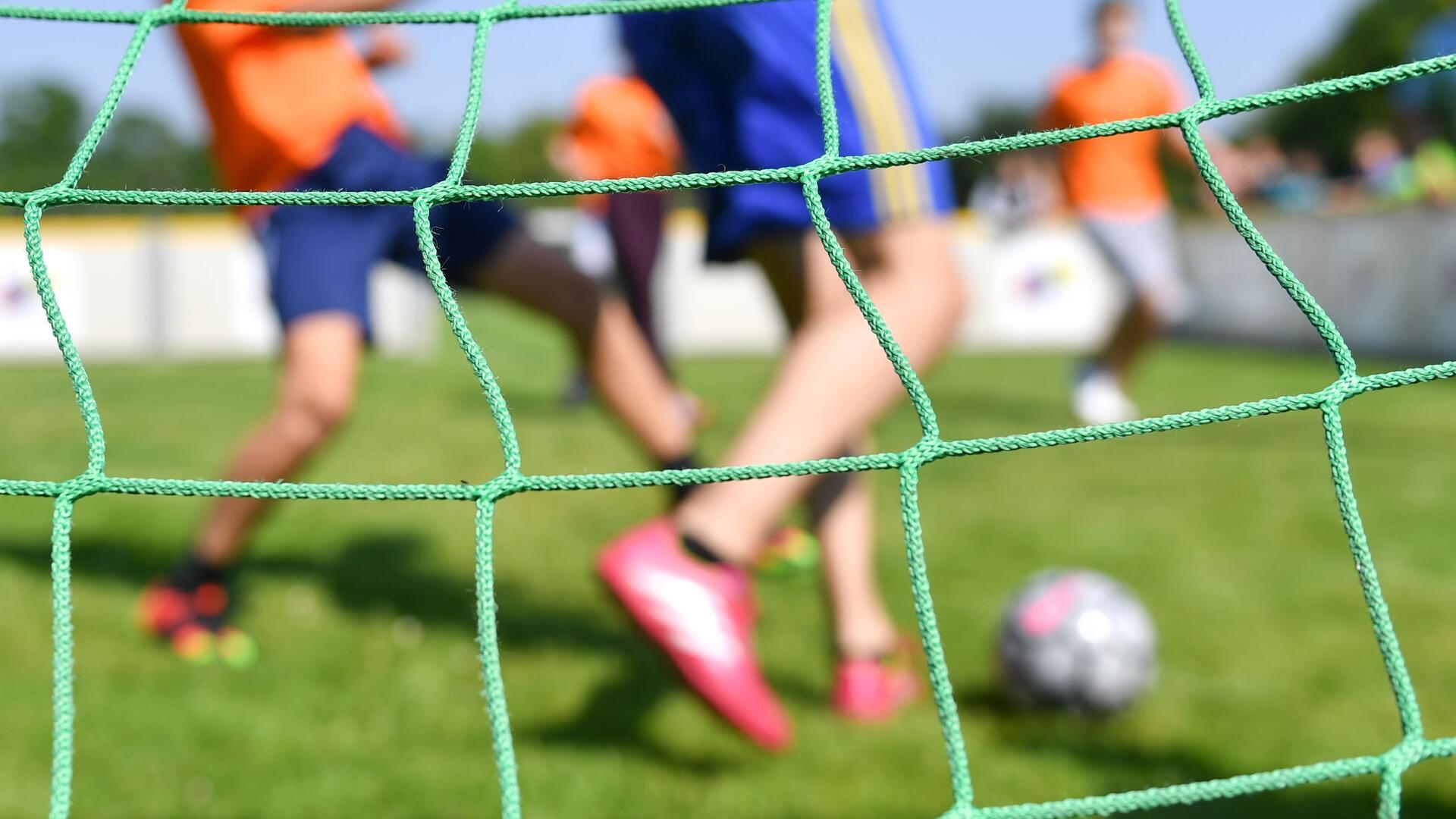  Kinder spielen auf einem Sportplatz Fußball. 