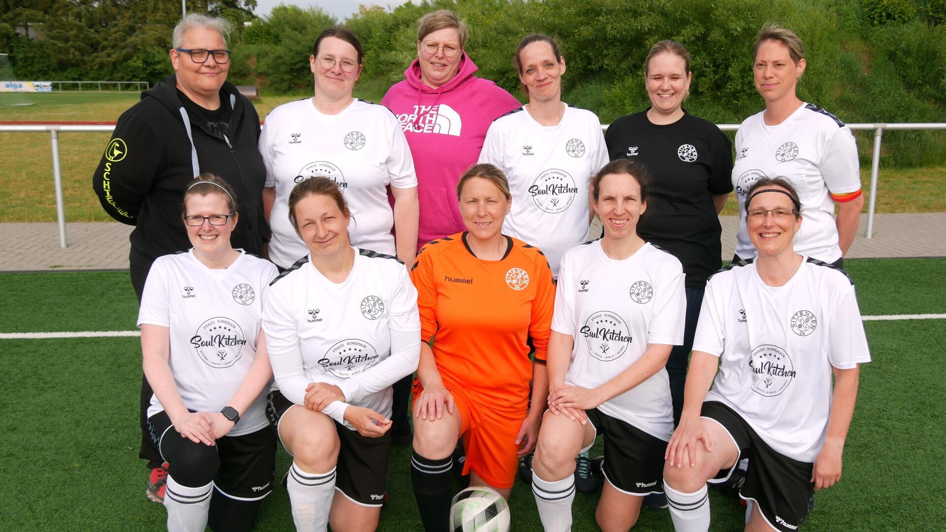 Elf Frauen in Sporttrikots stehen und knien in zwei Reihen.