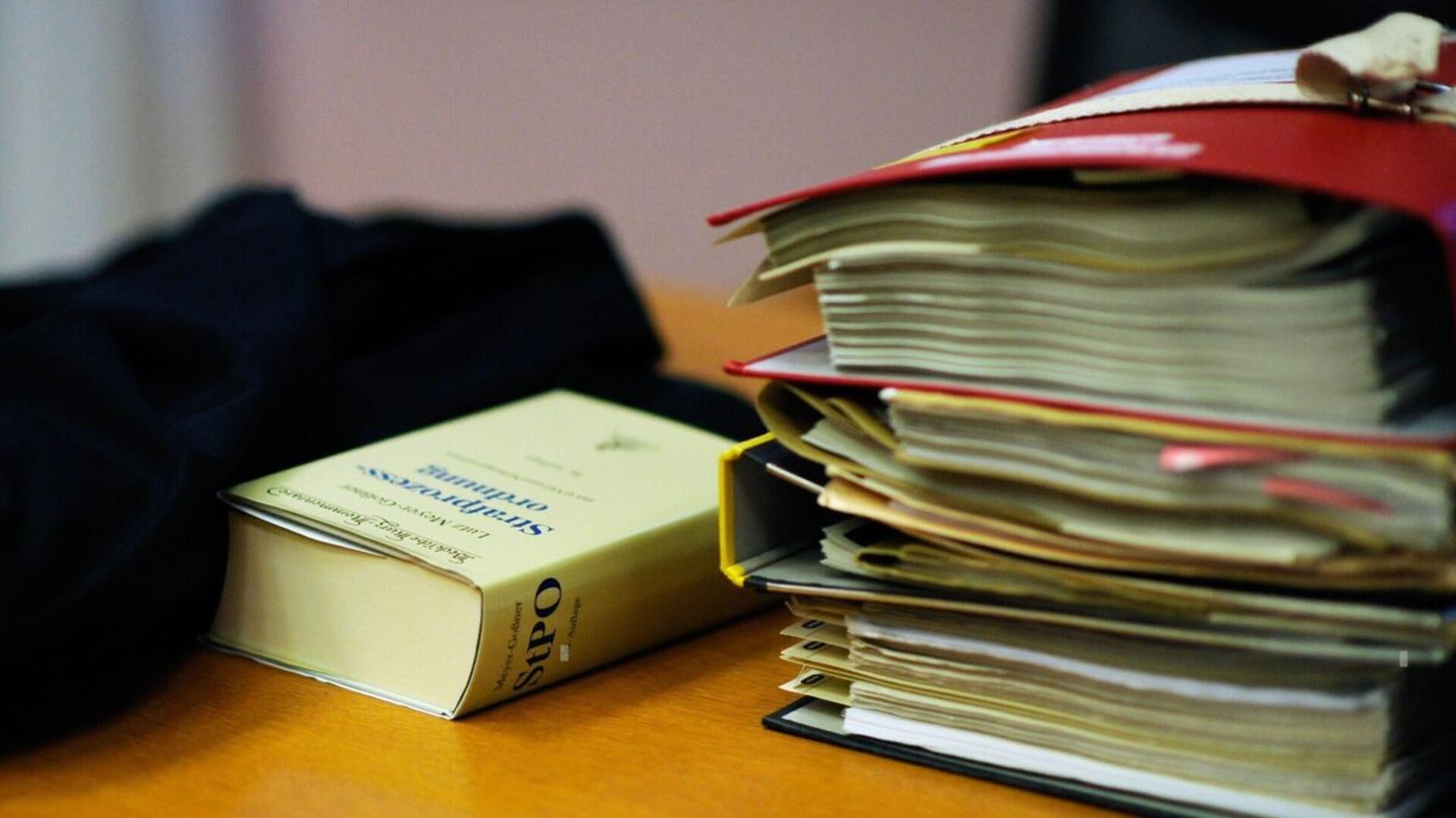 Akten und ein Gesetzbuch liegen auf dem Tisch eines Anwalts.