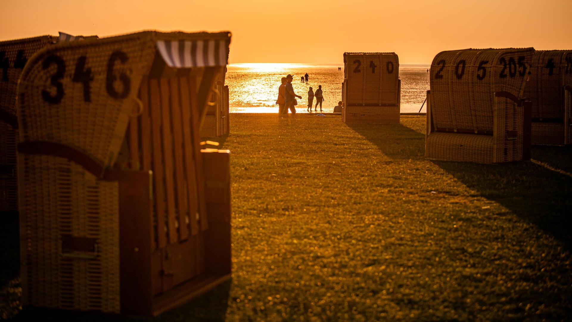 Menschen laufen an einem Strand in den Sonnenuntergang.