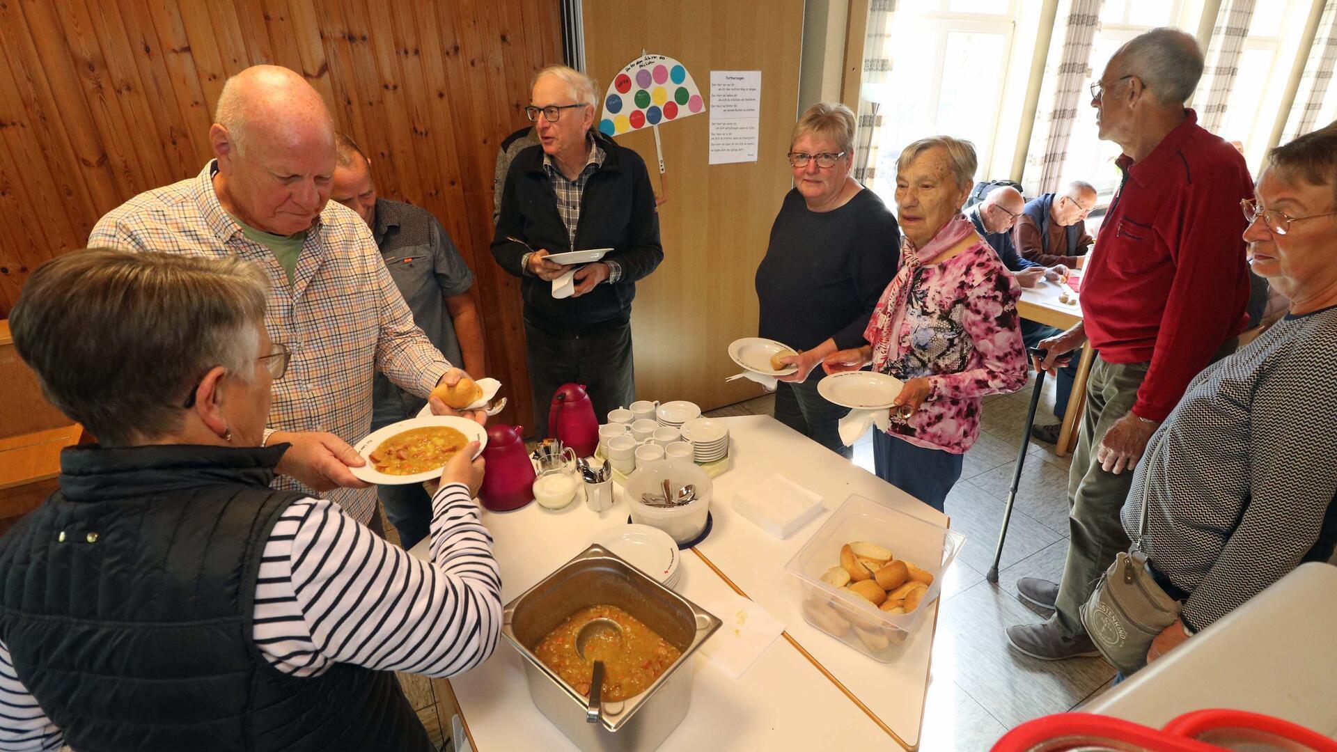 Mehrere Menschen stehen für einen Teller Suppe an