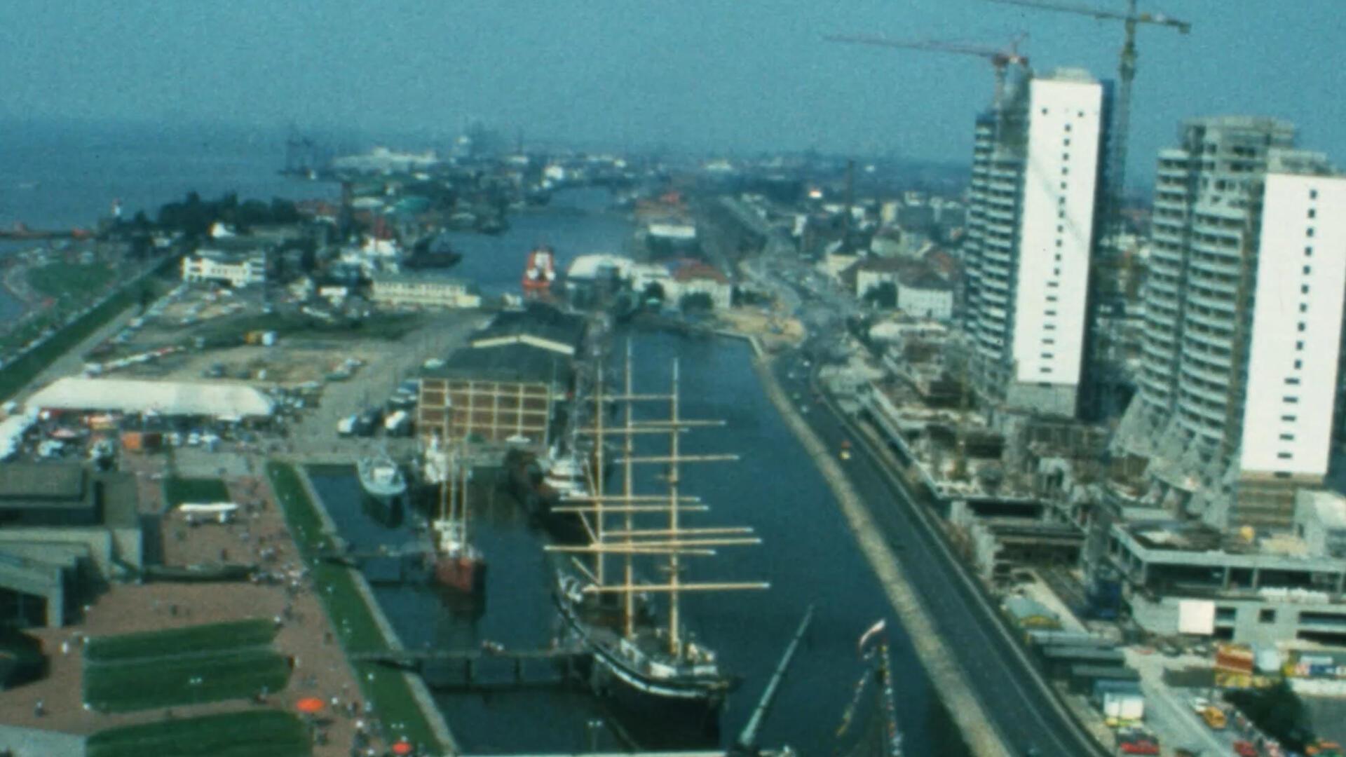 Luftaufnahme des Alten Hafens in Bremerhaven mit dem Museumsschiff „Seute Deern“, umliegenden Gebäuden und im Bau befindlichen Columbus Center, aus den 1970er-Jahren.