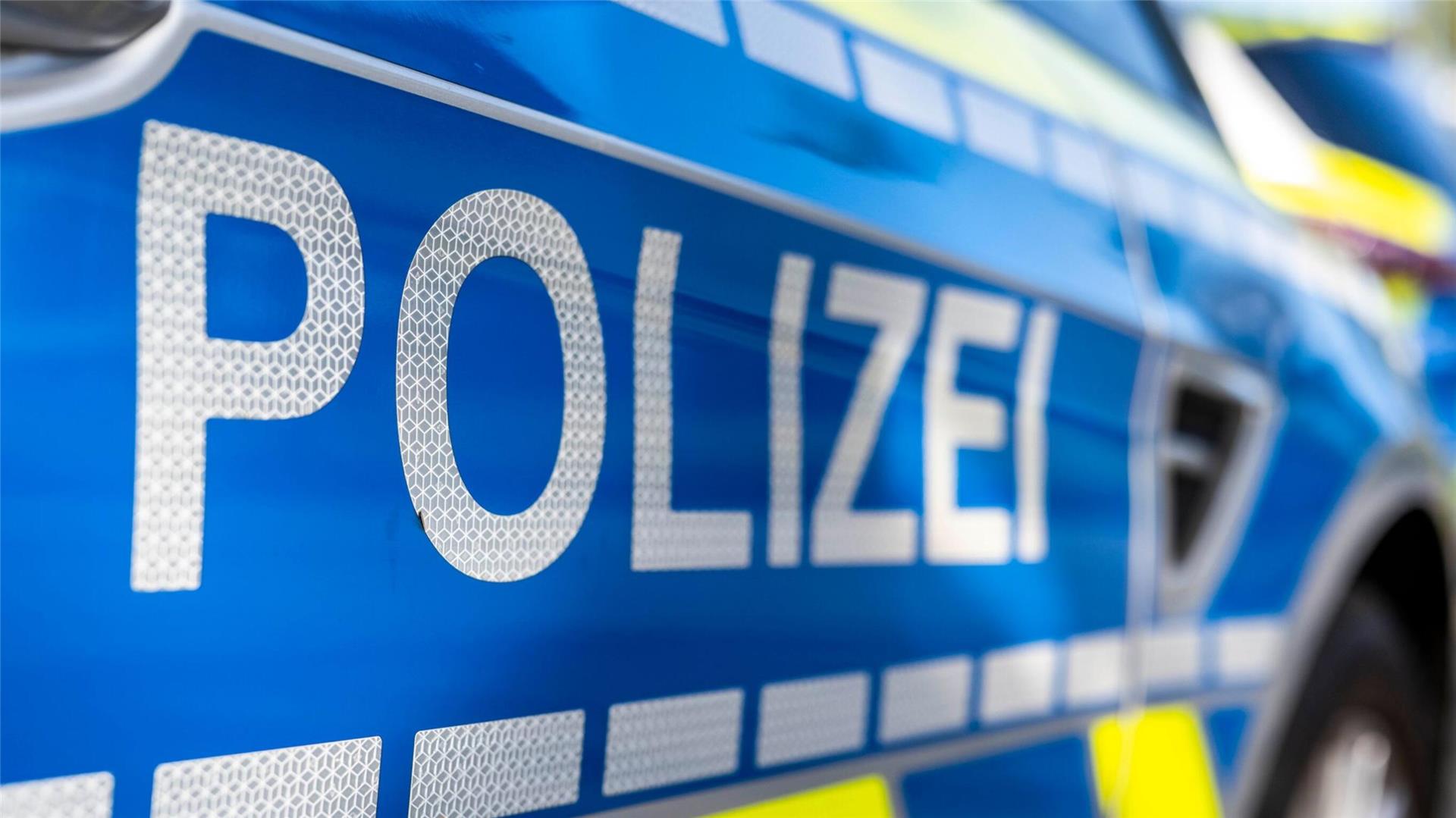  An der Tür von einem Streifenwagen steht der Schriftzug "Polizei". 