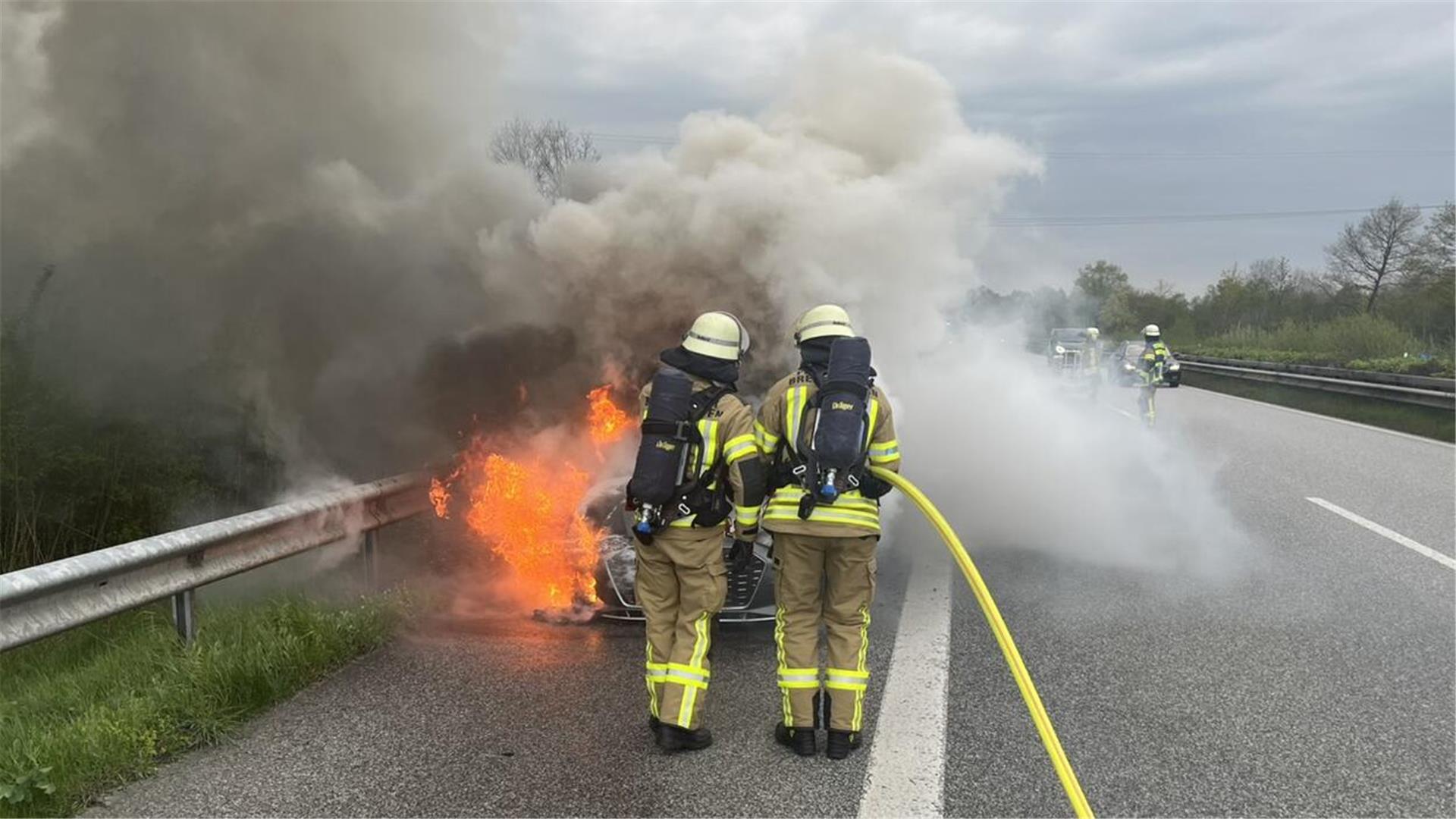 Einsatzkräfte der Feuerwehr löschen ein brennendes Auto. 
