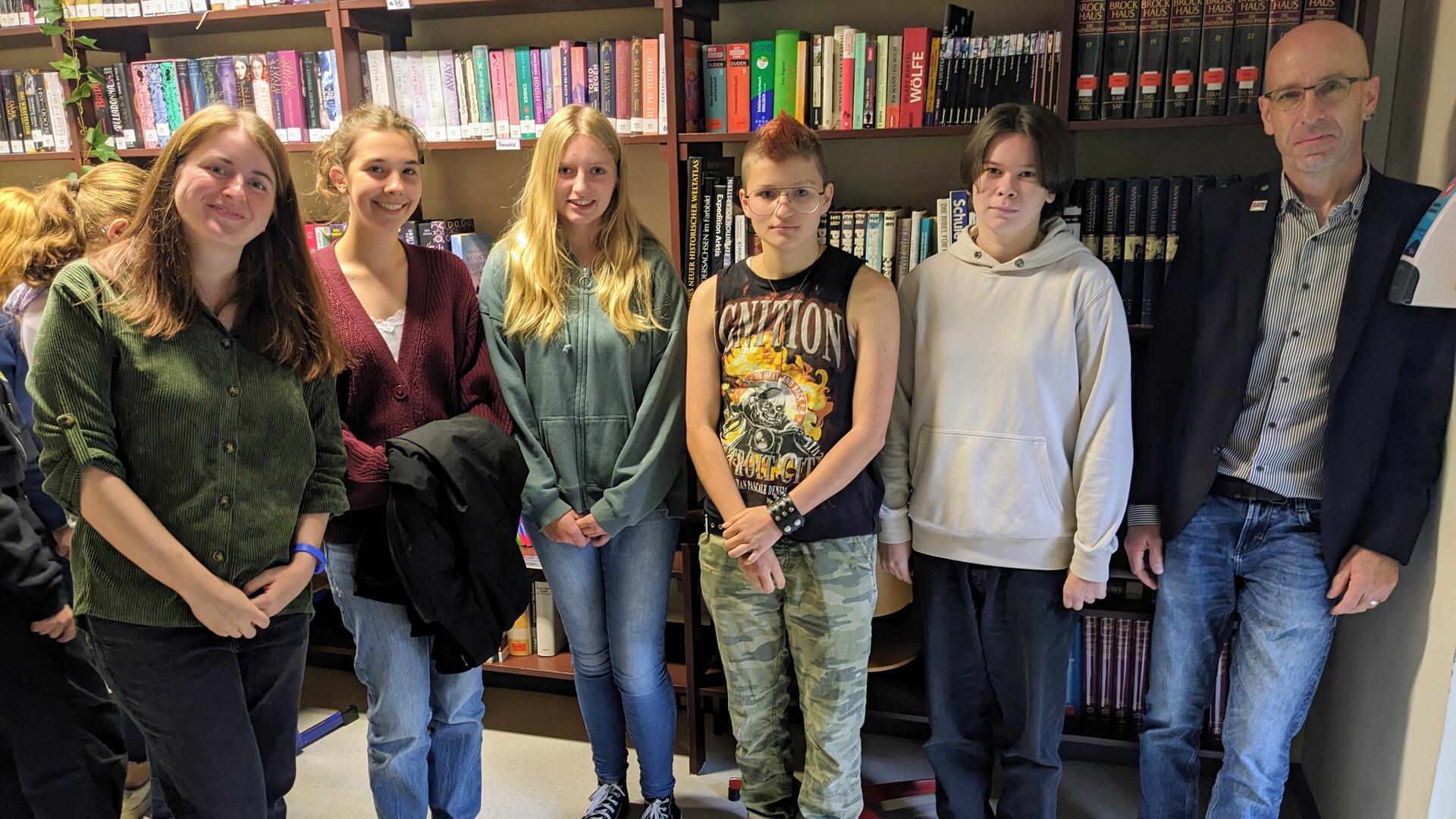 Mehrere Menschen stehen vor einem Bücherregal.