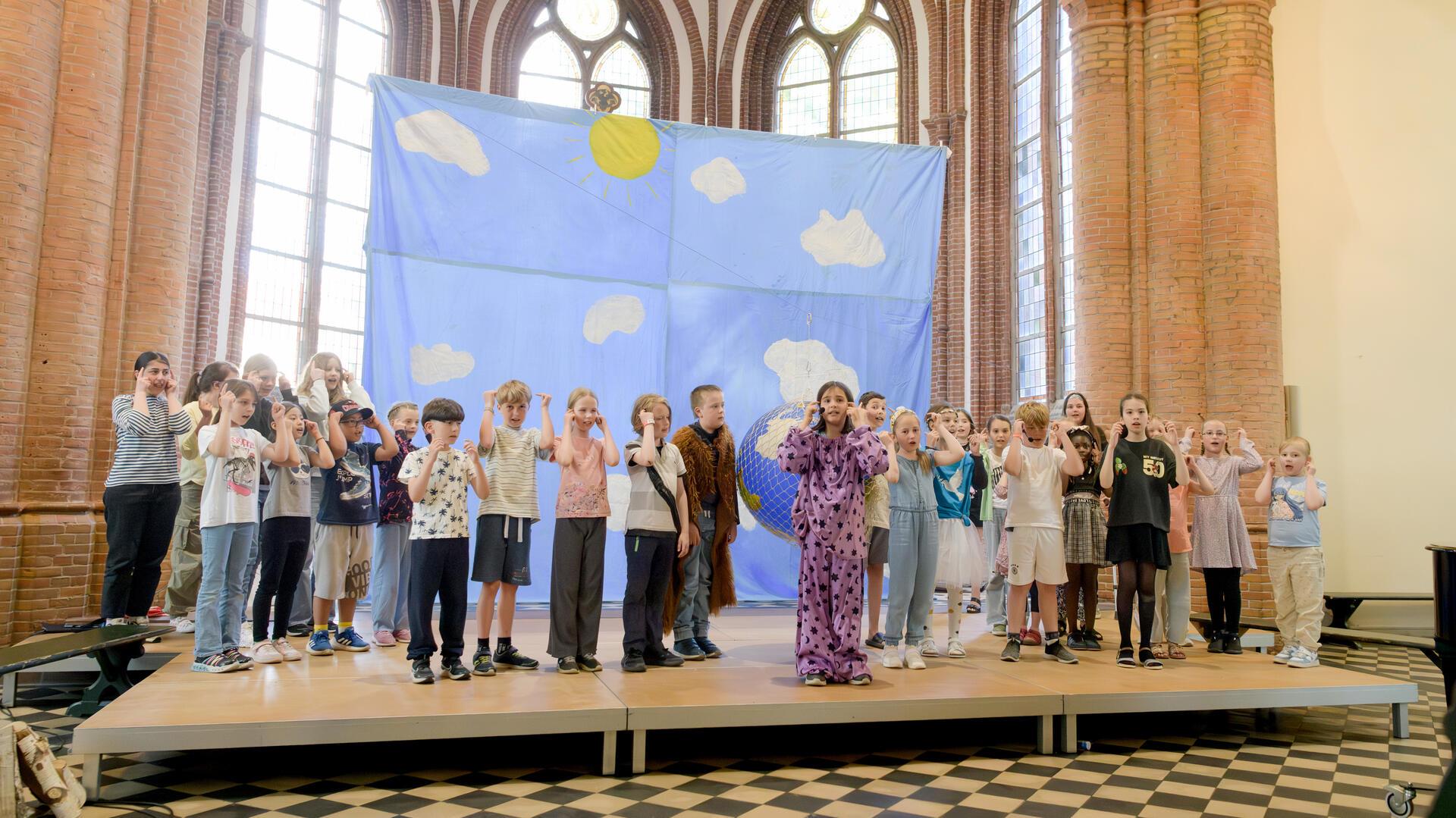 Mädchen und Jungen auf der Bühn vor dem Altar