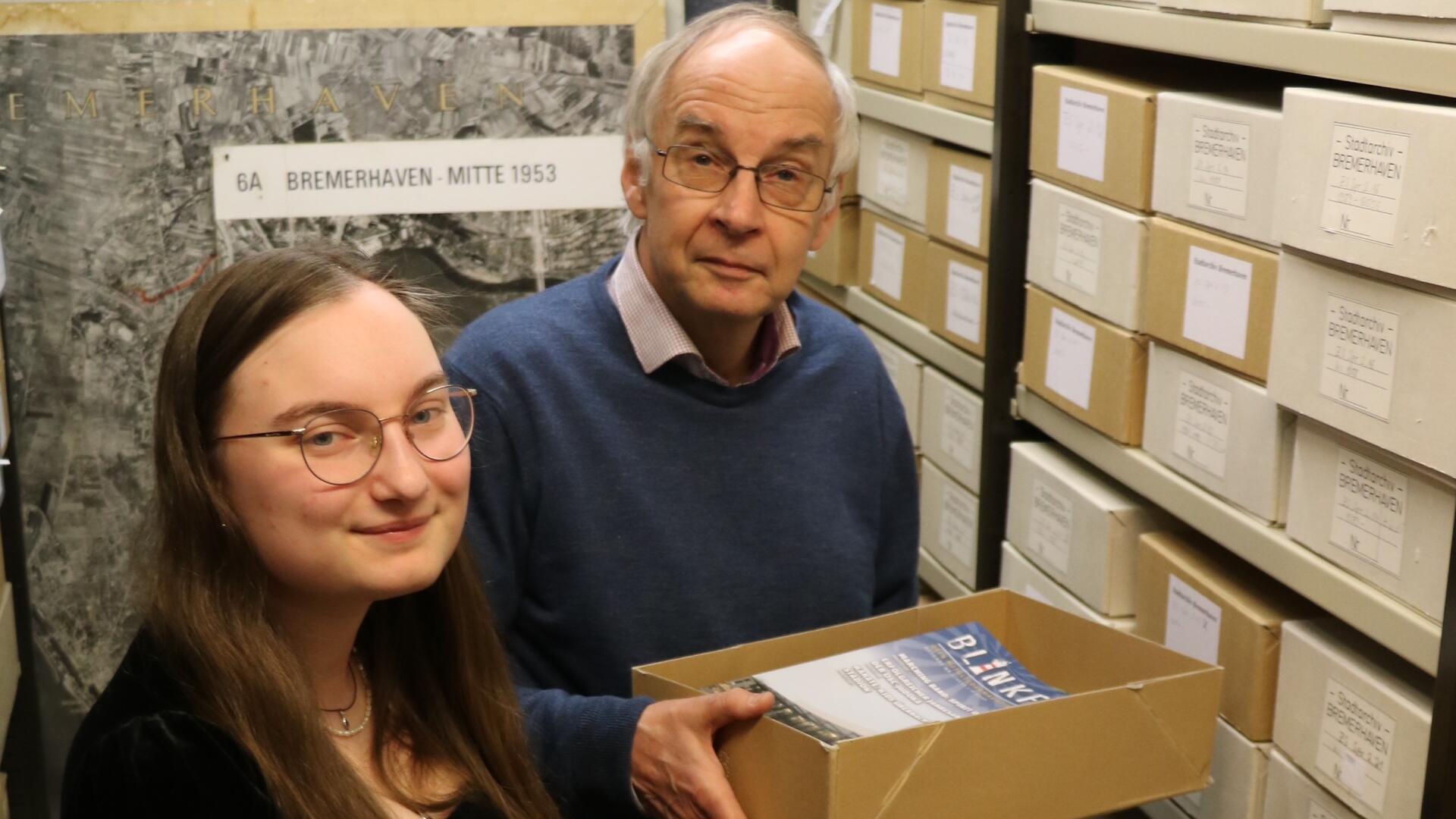 Stadtarchivar Uwe Jürgensen steht mit seiner Nachfolgerin Lea Schnelle neben Akten im Stadtarchiv der Stadt Bremerhaven. 